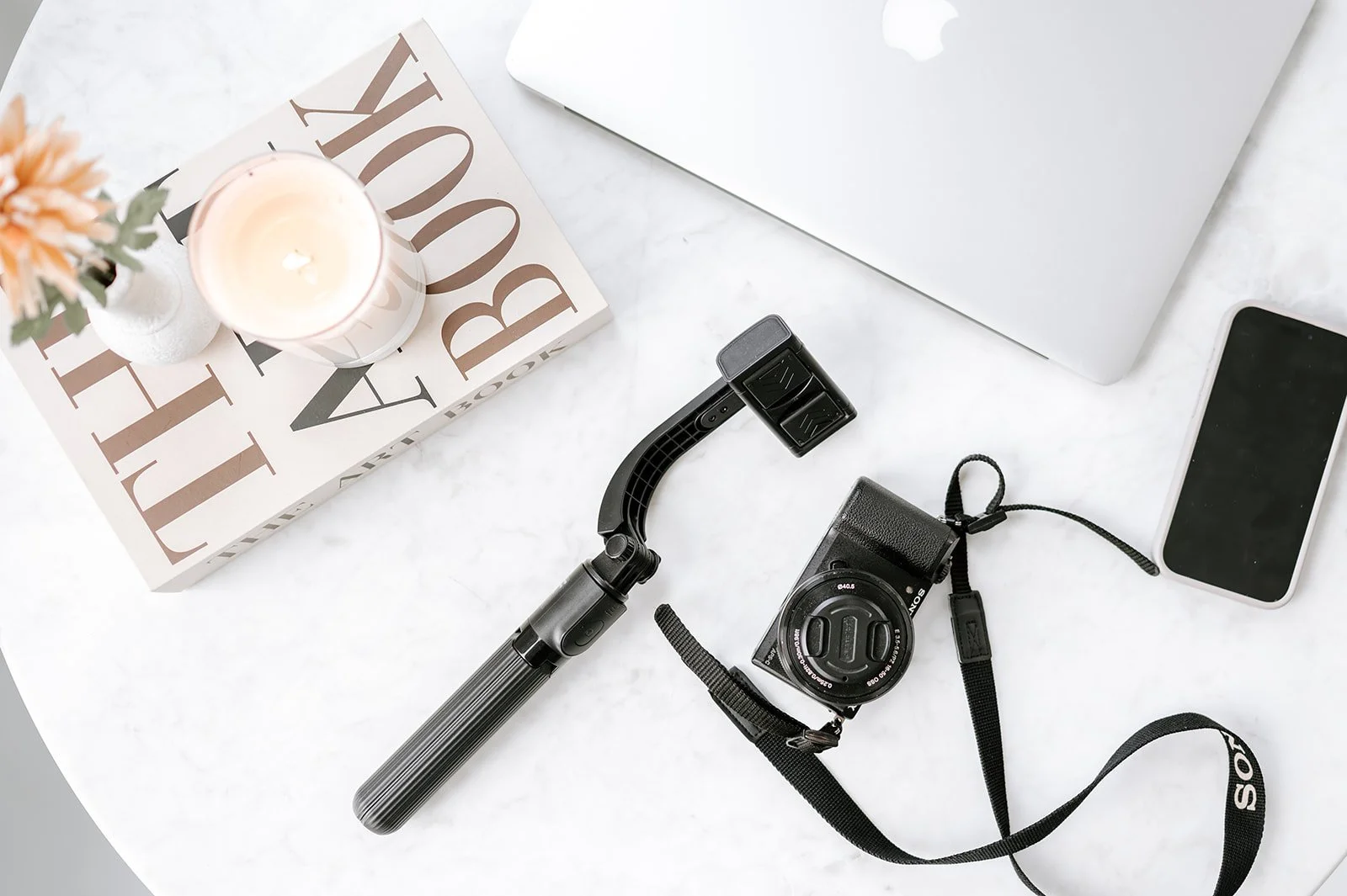 Workspace with camera, laptop, and creative tools on a clean surface.