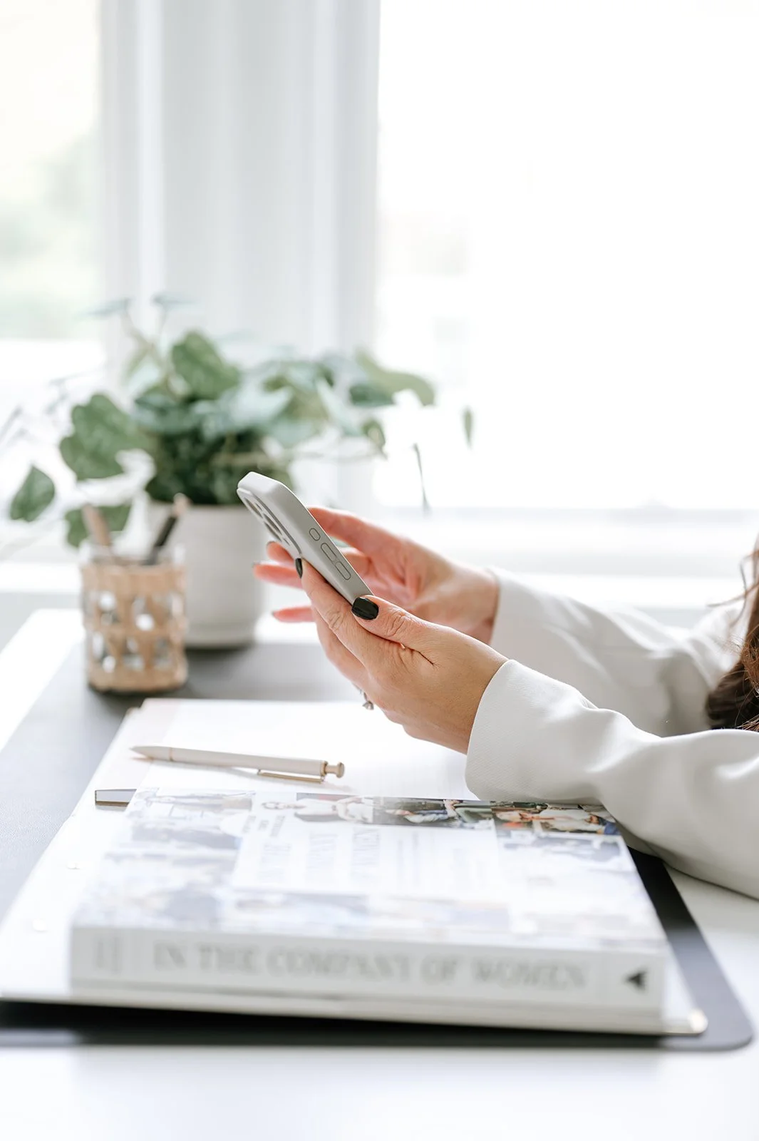 Close-up of hands using a phone in a workspace, representing marketing coordination and campaign management across platforms.