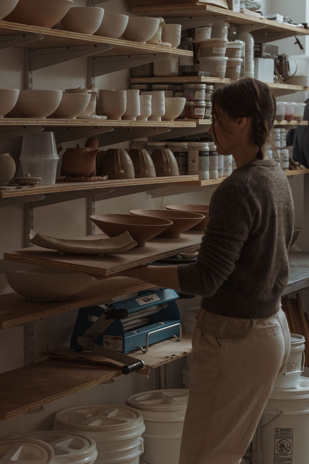 ceramic artist Katya at Aculina moves a shelf with greenware pieces