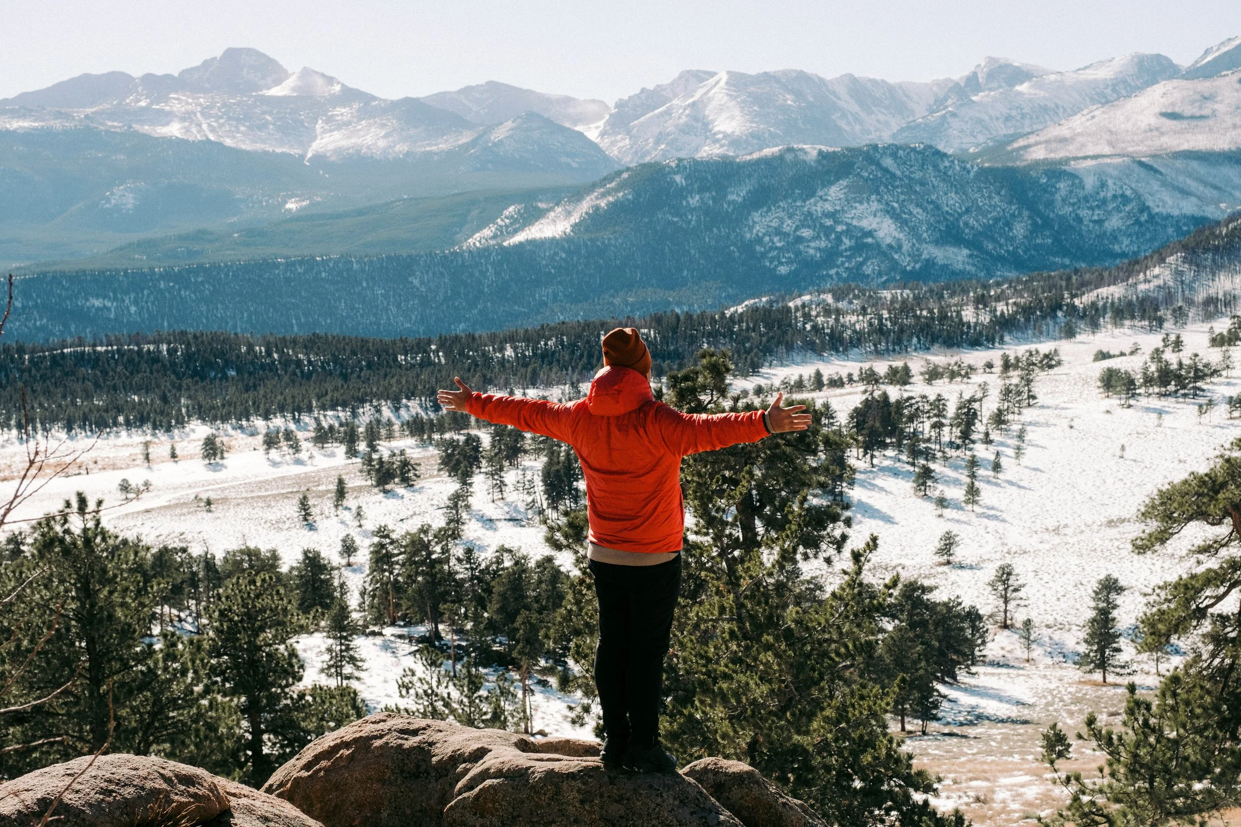 Photo of man overlooking snowcapped mountains.