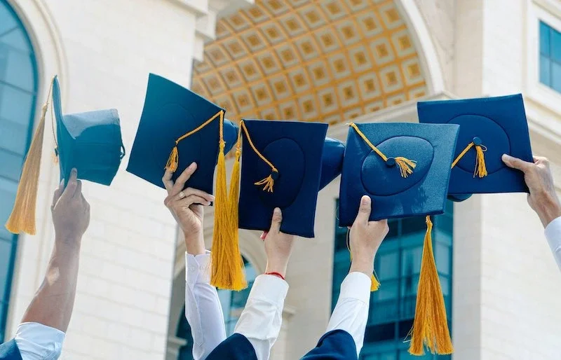 people holding up graduation hats