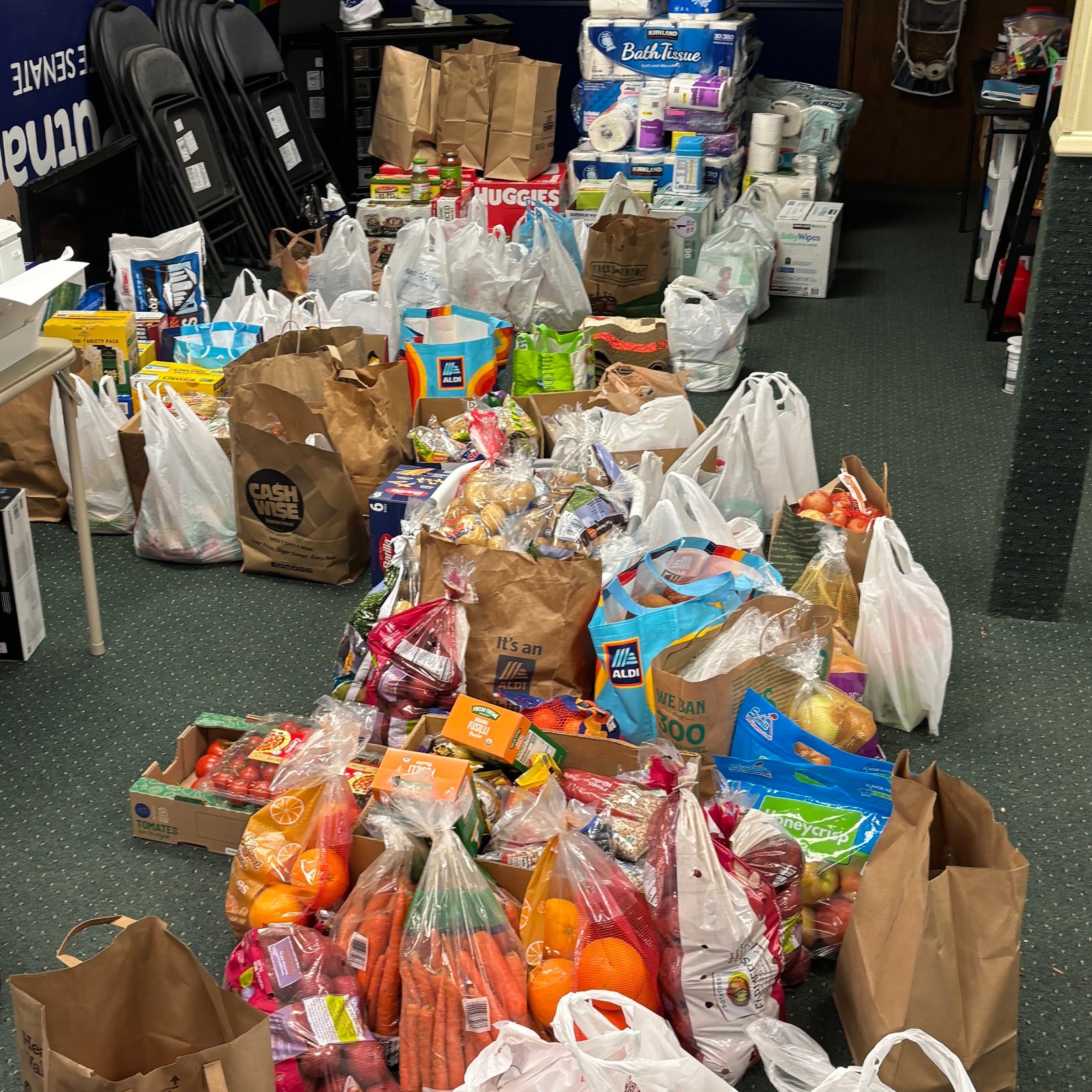 Multiple grocery bags and boxes filled with fresh produce, toiletries, and household items in a store aisle.