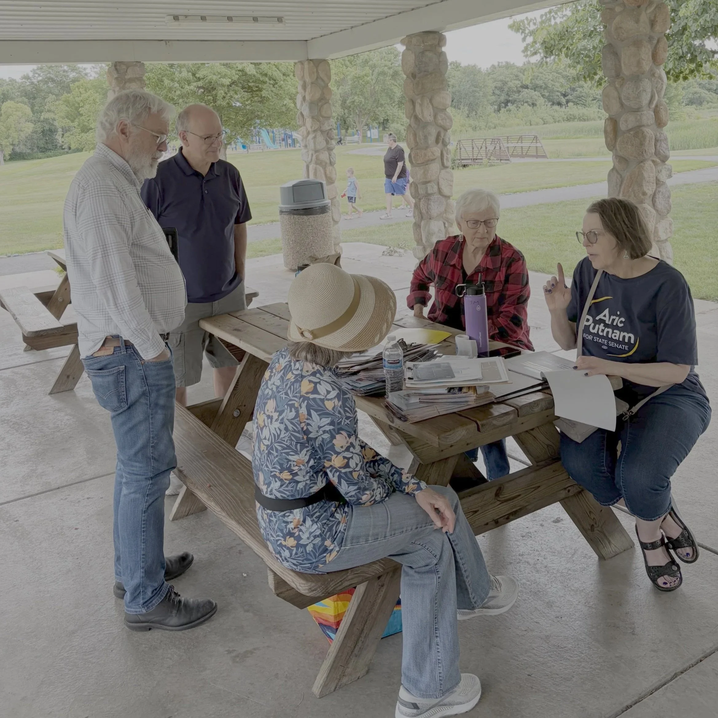 A voluteer for the Aric Putnam campaign has a conversation with community members in a park
