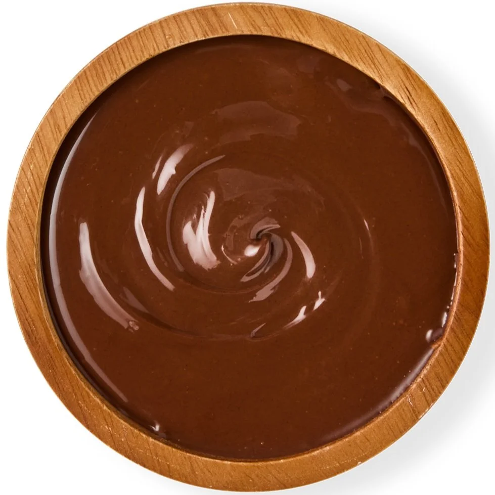 A bowl of melted dark chocolate in a wooden container.