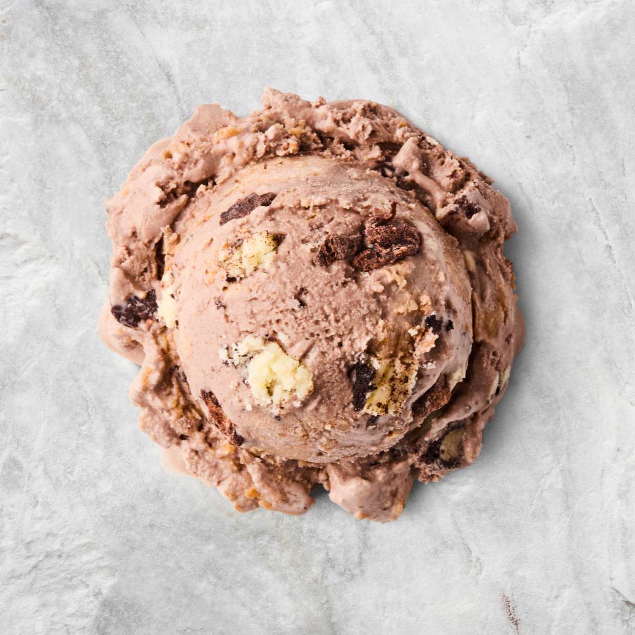 A scoop of chocolate chip ice cream on a white surface.