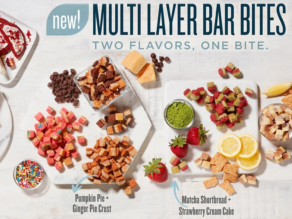Multiple plates of multicolor layered bar bites with various toppings, including pumpkin pie and ginger pie crust, matcha shortbread, strawberry cream cake, strawberries, lemon slices, and colorful sprinkles, with text indicating new multi-layer bar bites with two flavors in one bite.