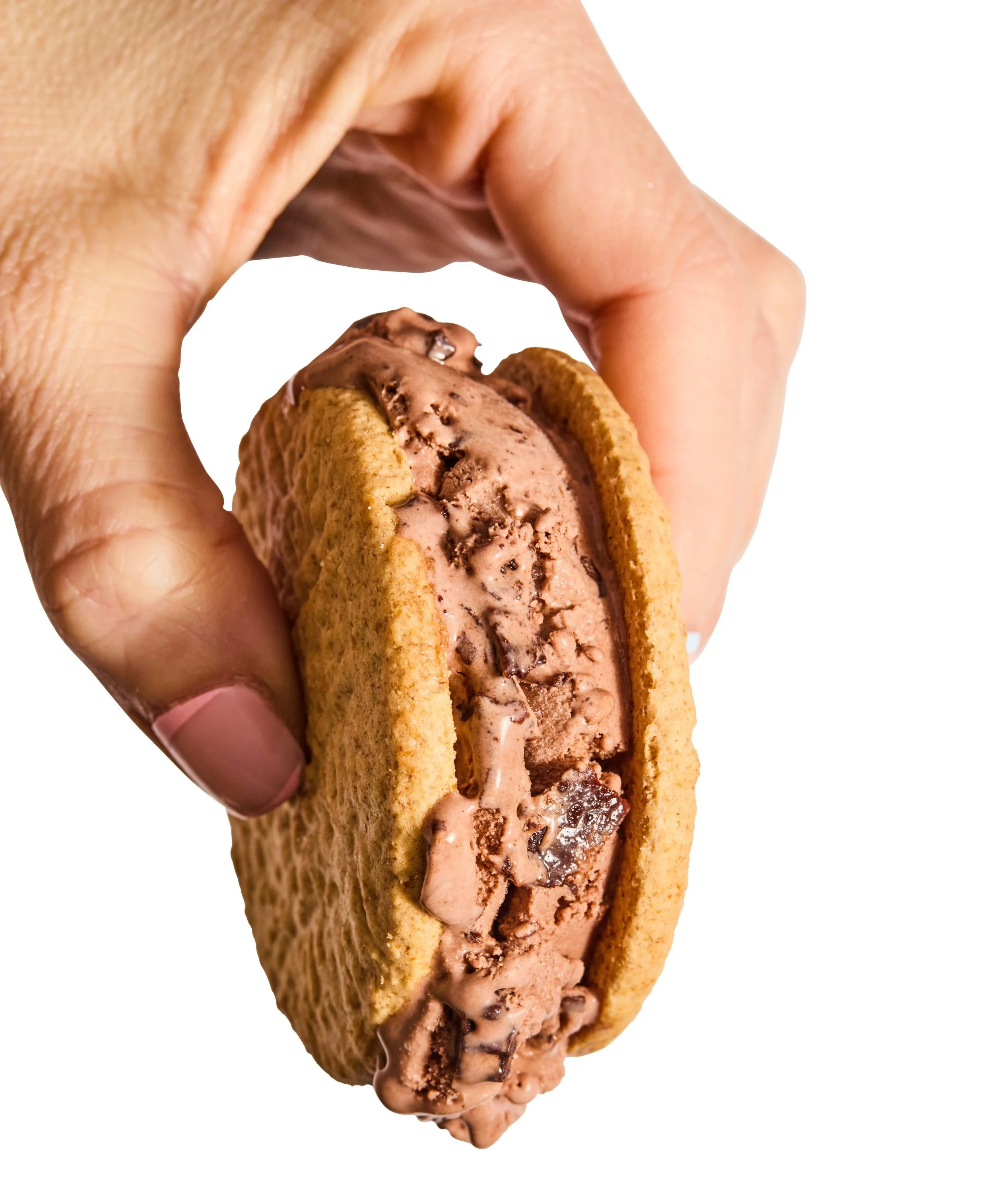 Hand holding a chocolate ice cream sandwich with cookies and chocolate ice cream inside.