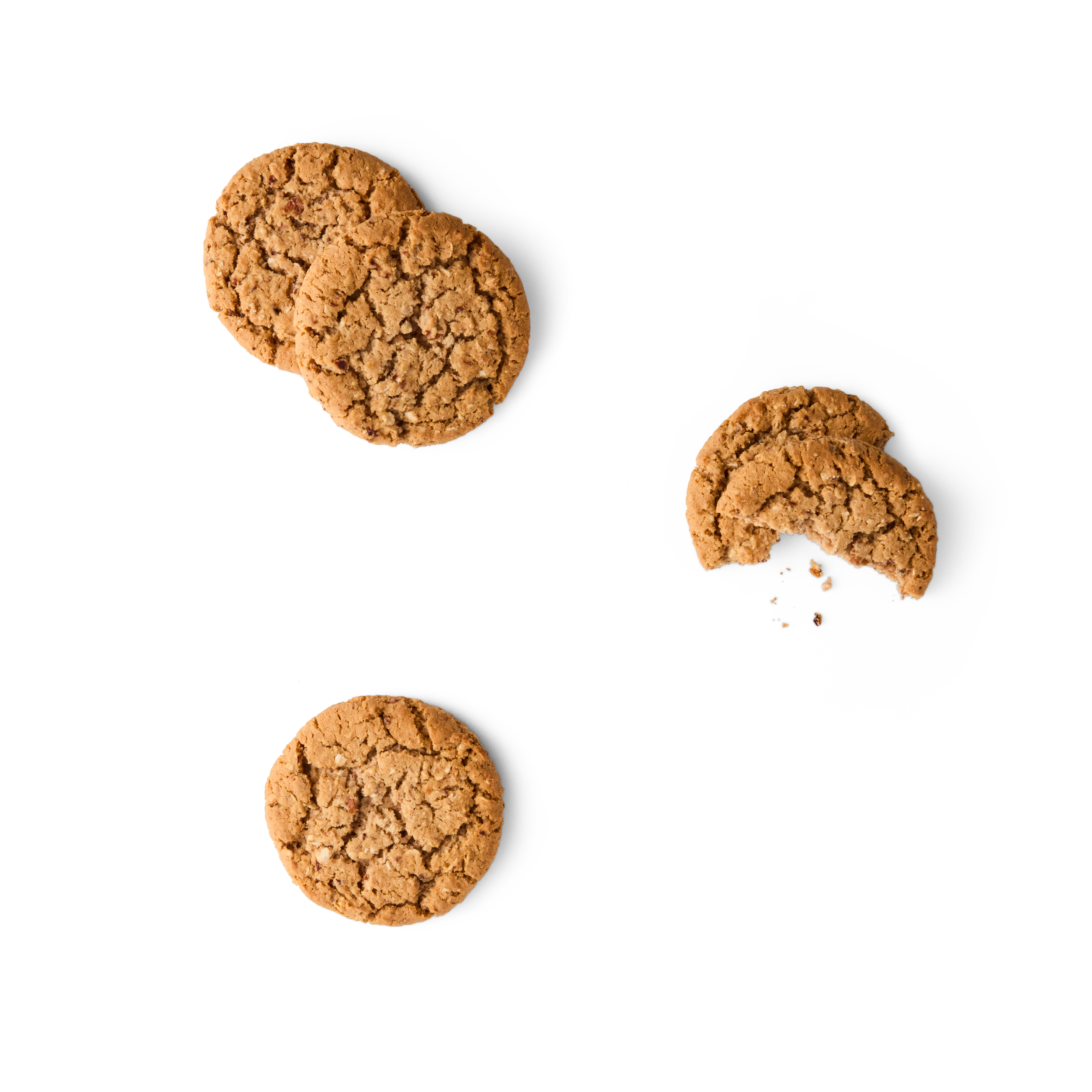 Three oatmeal cookies, two whole and one broken with crumbs, on a white surface.