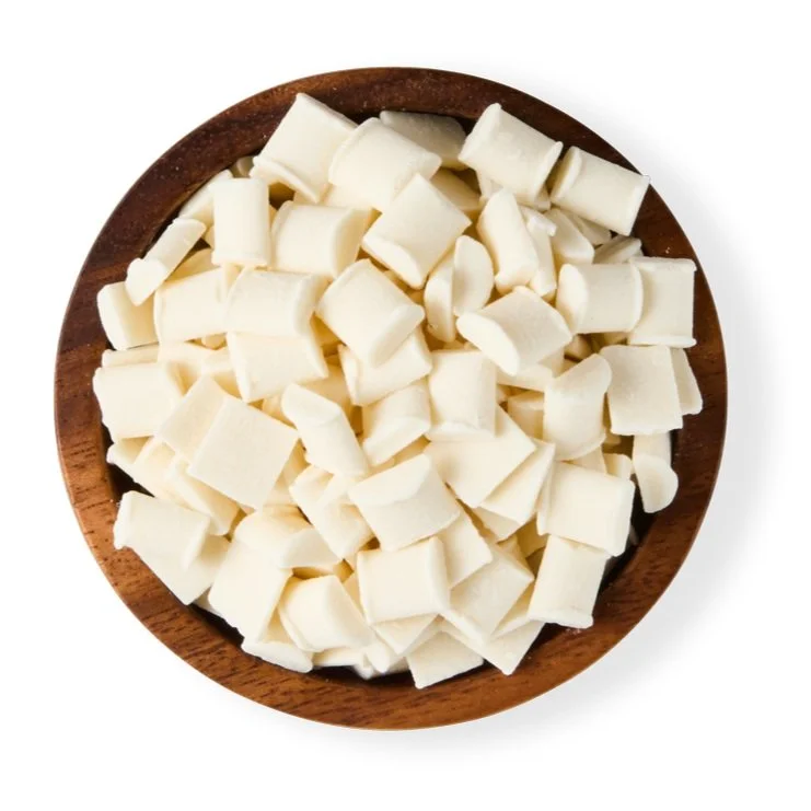 White chocolate chunks in a wooden bowl against a white background.