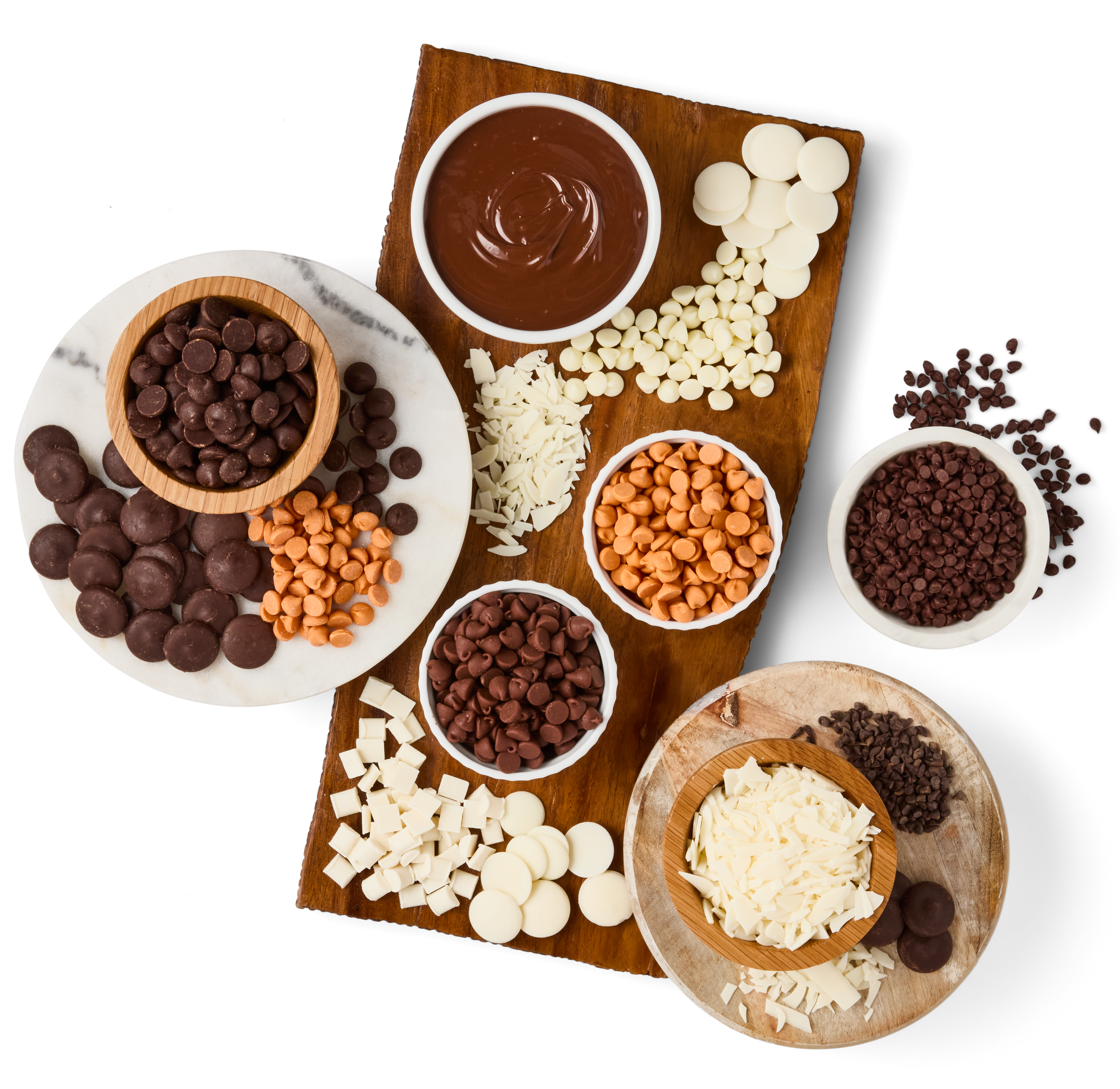 Assorted chocolate chips, white chocolate, and chocolate melts on wooden and marble boards.