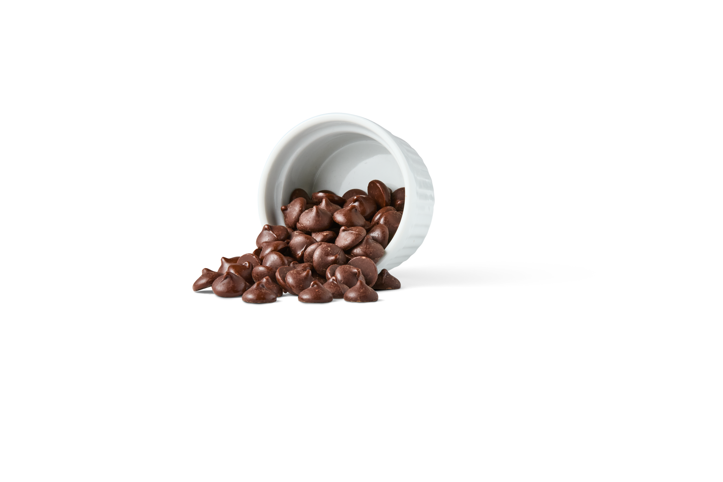 Chocolate chips spilling from a white container onto a surface.