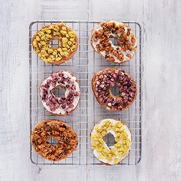 Six donuts with various toppings on a wire rack