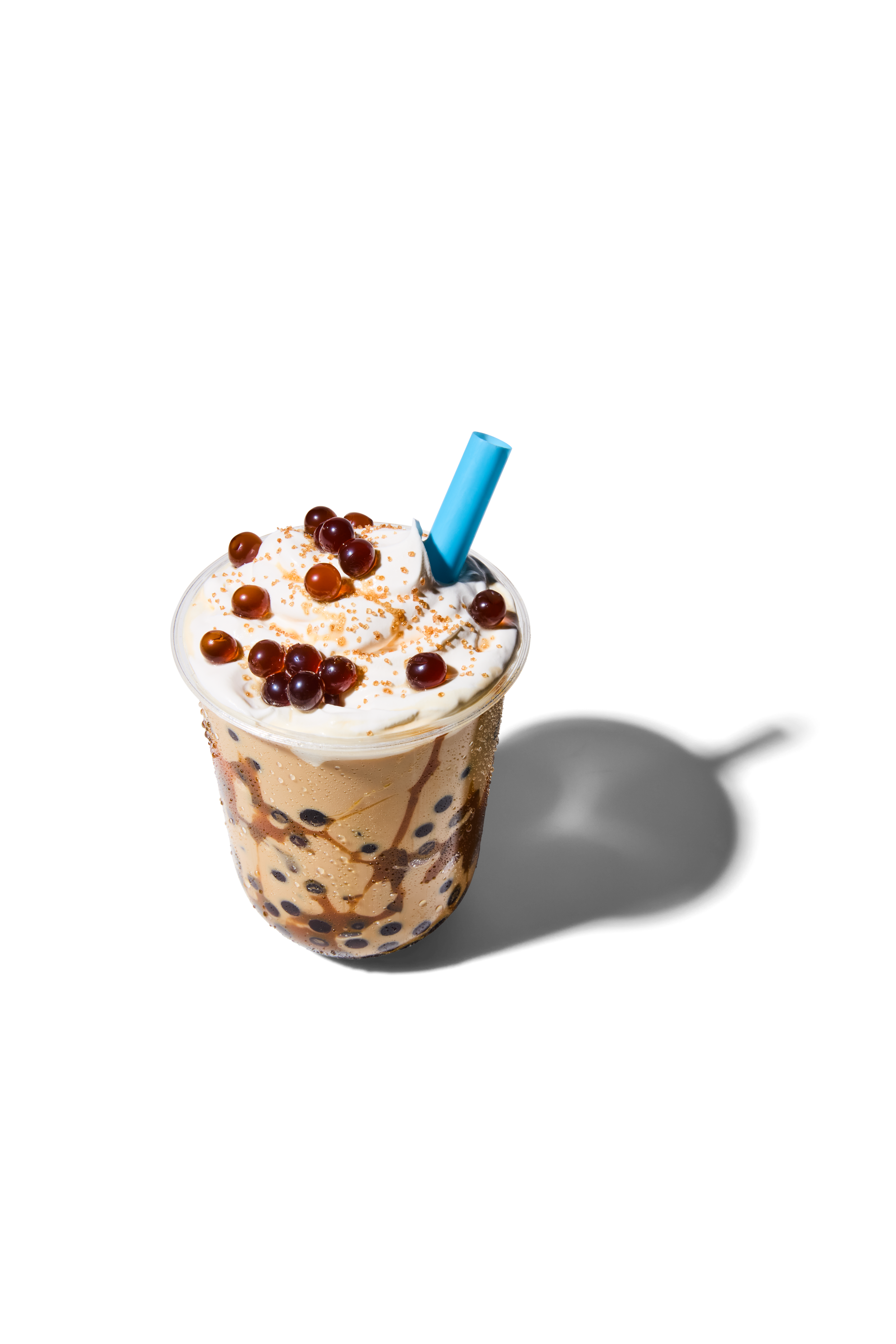 A cup of bubble tea with whipped cream, tapioca pearls, and chocolate drizzle, with a blue straw.