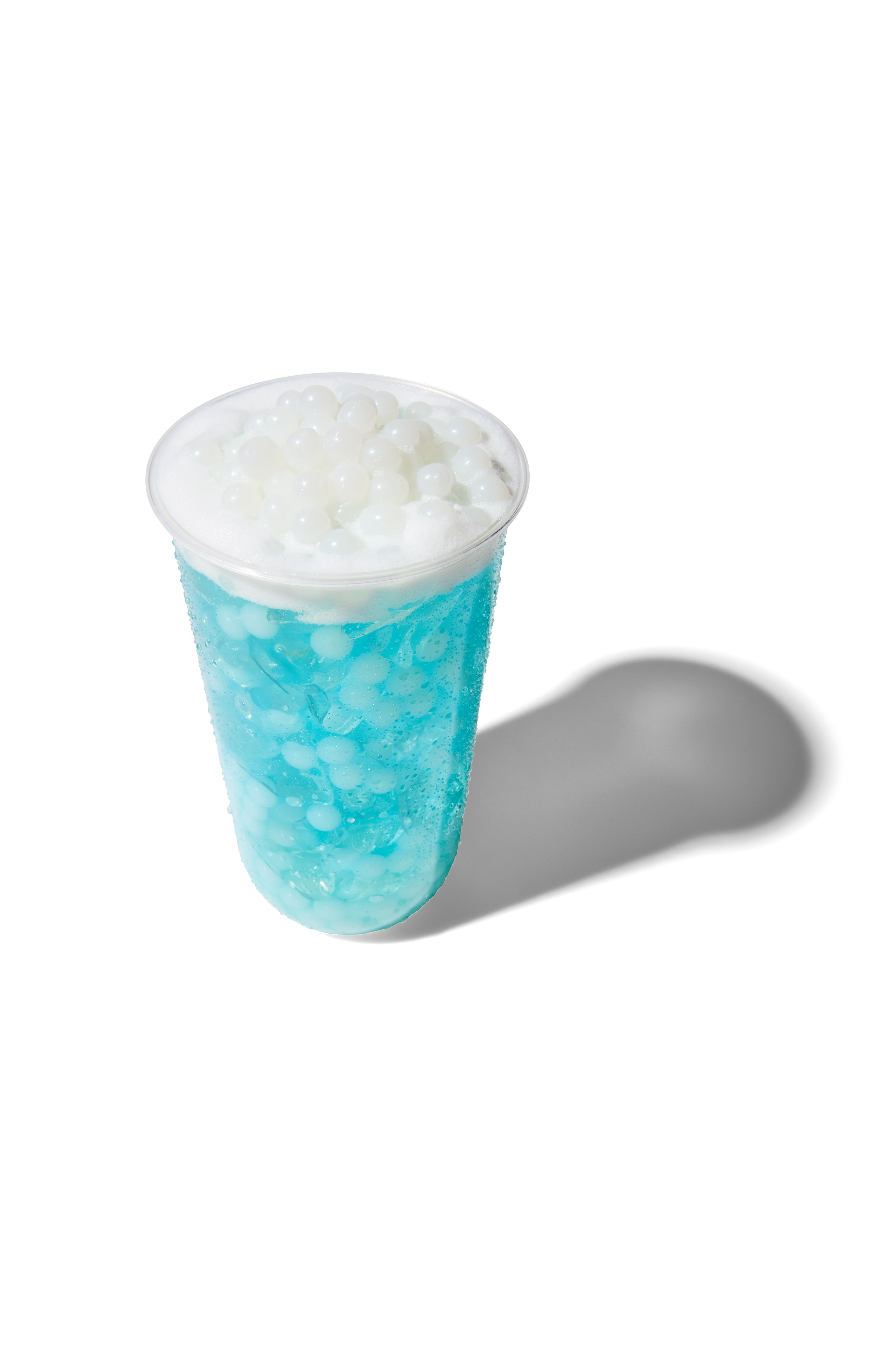 Blue bubble tea with white tapioca pearls in a clear plastic cup with a domed lid
