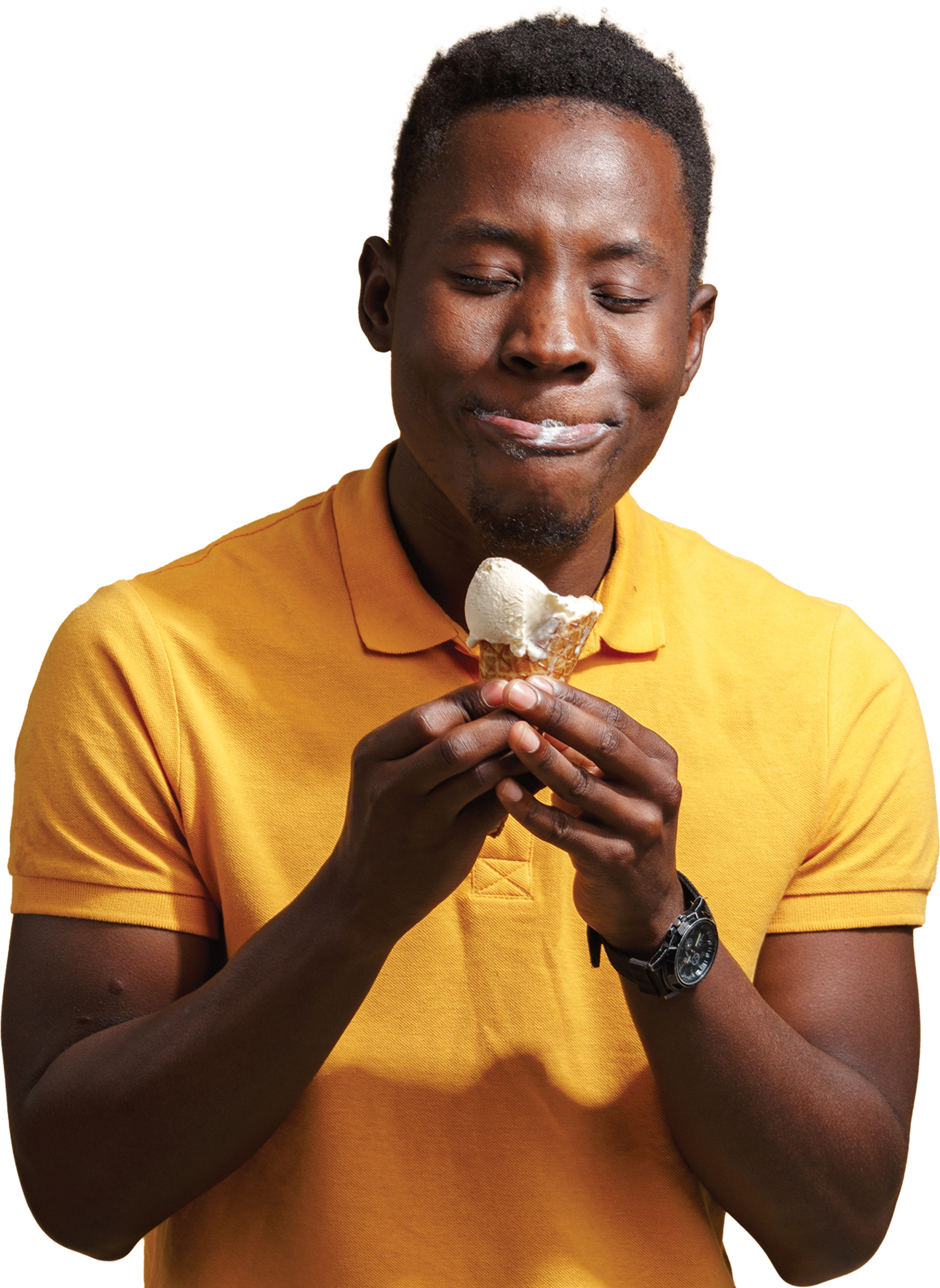 A man with dark skin and short curly hair wearing a yellow polo shirt, holding an ice cream cone, with his eyes closed and a smile.