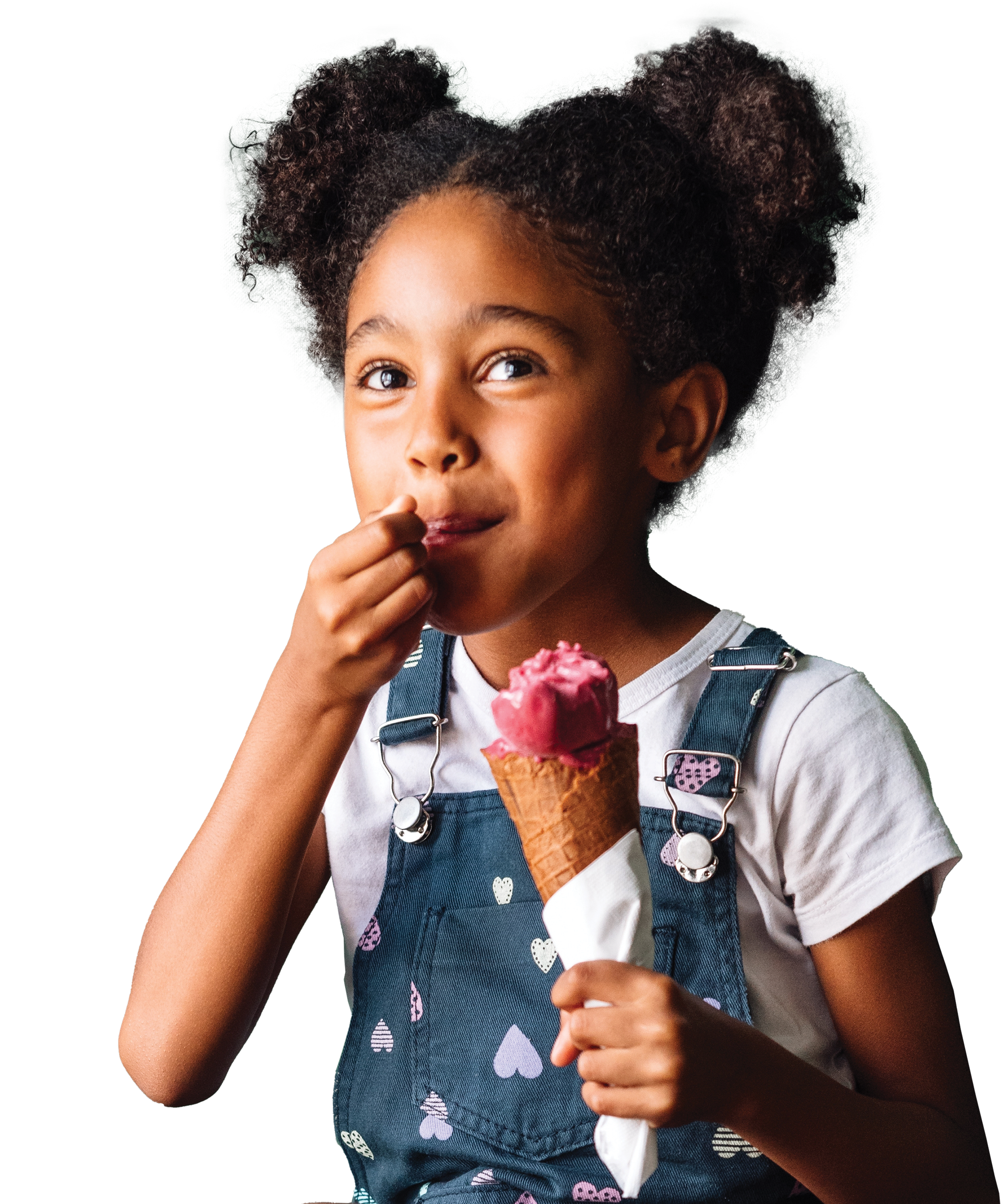 A young girl with curly hair in puffs enjoying pink ice cream cone.