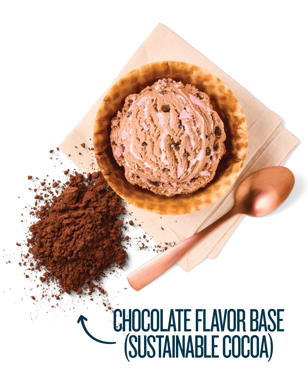 Chocolate ice cream with pink and chocolate chips in a waffle cone, surrounding by cocoa powder, on a beige napkin with a copper spoon.
