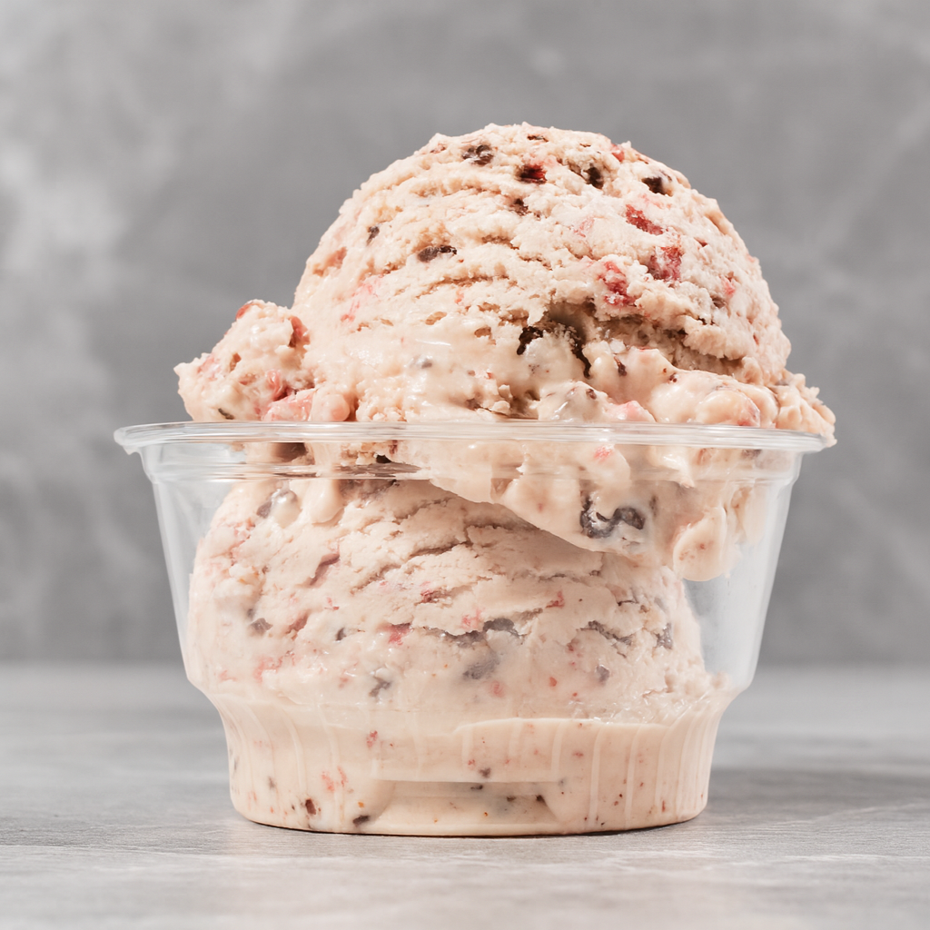 A bowl of strawberry ice cream with mixed berries, in a clear container.