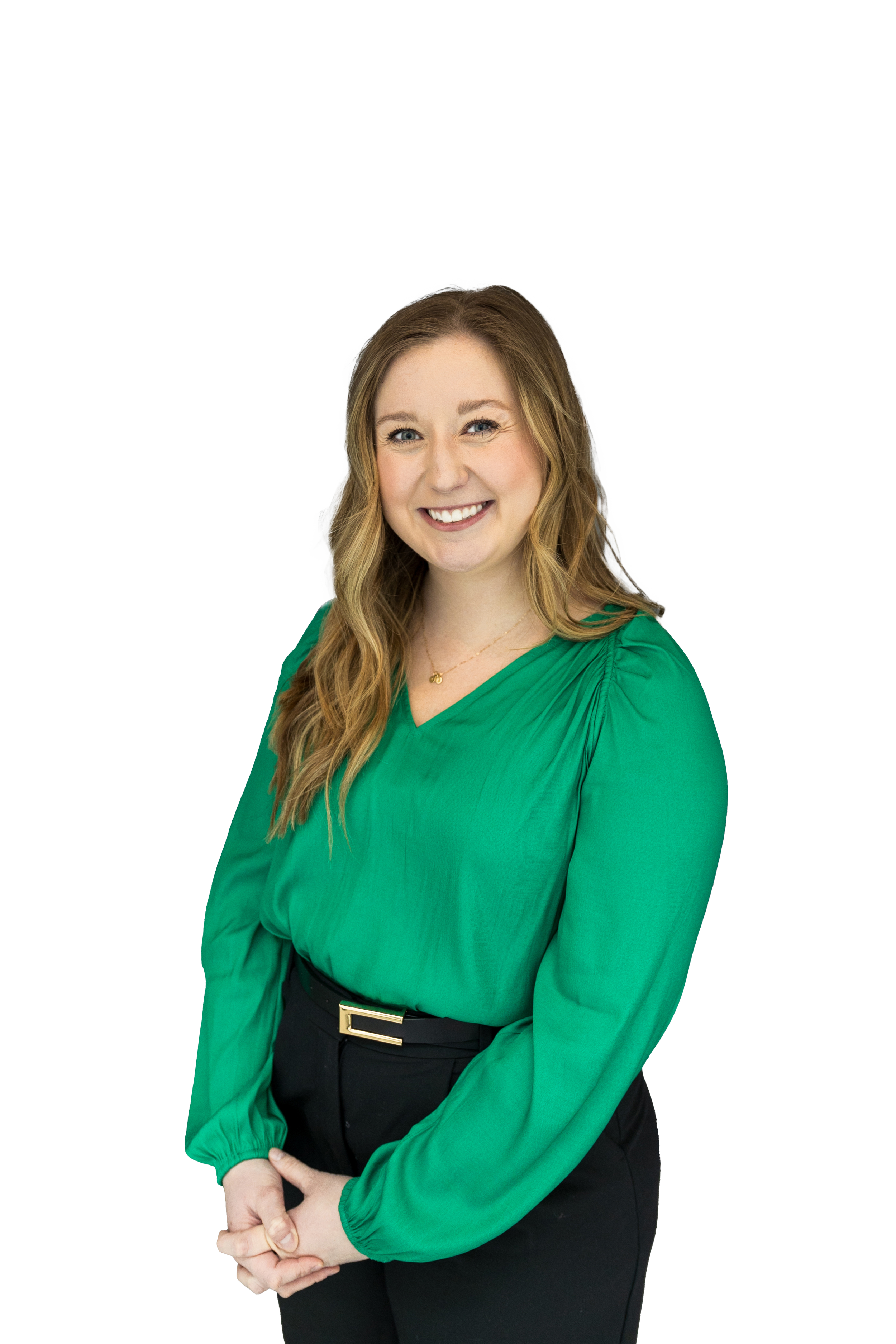 A woman with long wavy blonde hair smiling, wearing a green long-sleeved blouse with a V-neck, black pants, and a gold belt buckle, standing against a background with color blocks of black, white, and green.