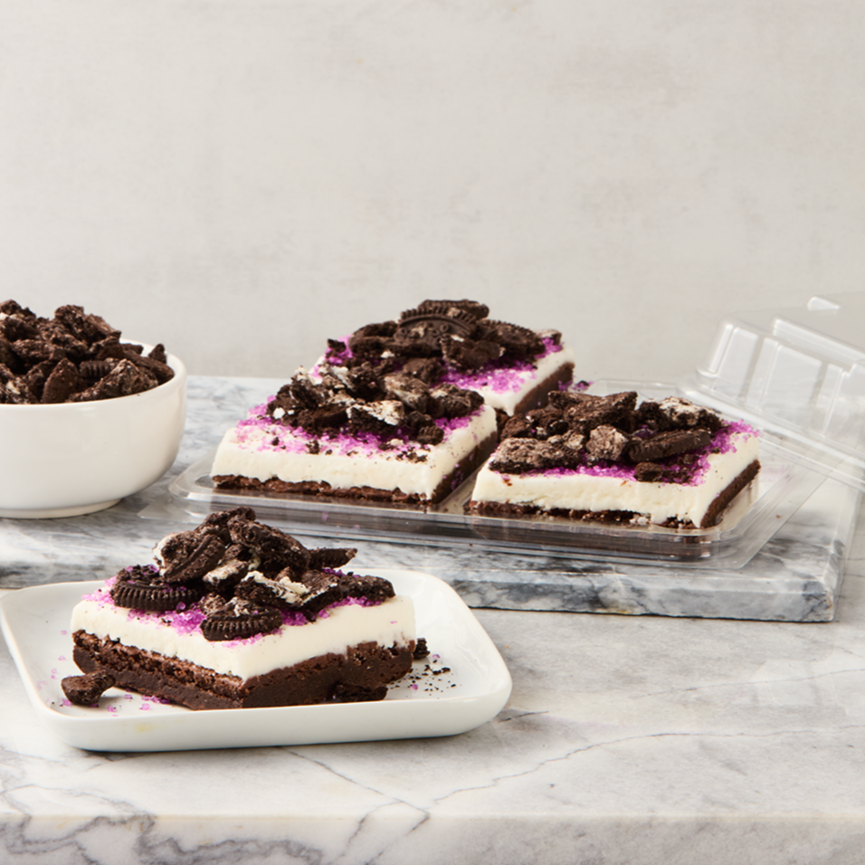 Chocolate Oreo cheesecake bars topped with crushed Oreos and pink sprinkles on a marble surface.