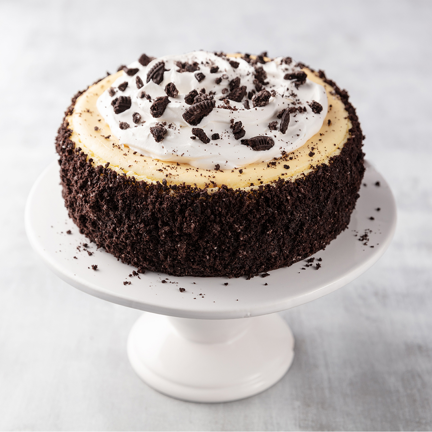 Chocolate cupcake with cookies and cream topping on a white cake stand.