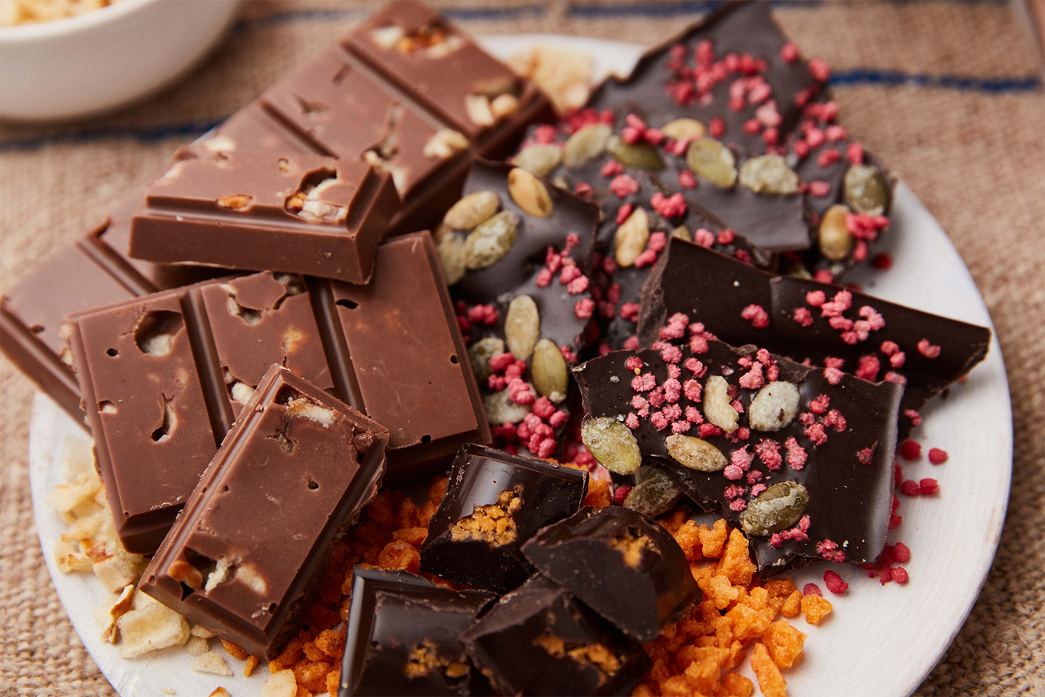 Assorted chocolate pieces with nuts and pink sprinkles on a white plate