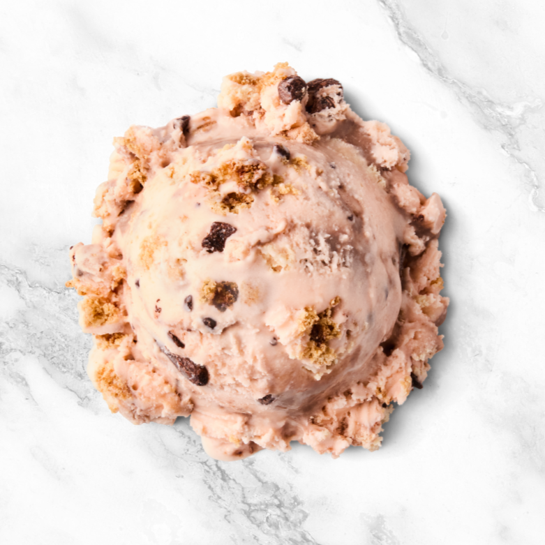 Scooped chocolate chip cookie dough ice cream in a round shape with cookie dough chunks, on a white marble surface.