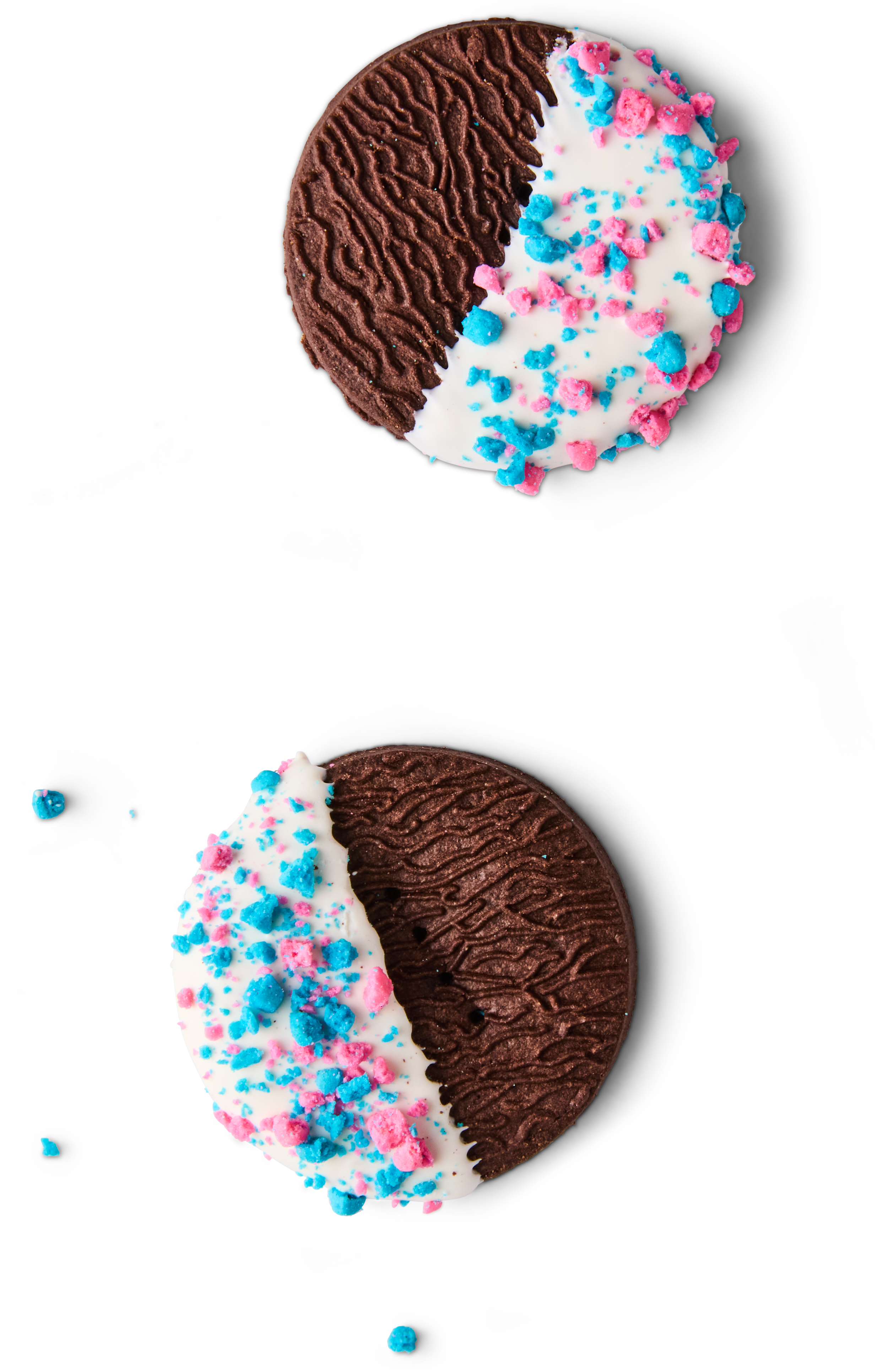 Round cookies with half chocolate frosting and half white frosting decorated with pink and blue sprinkles, on a black background.