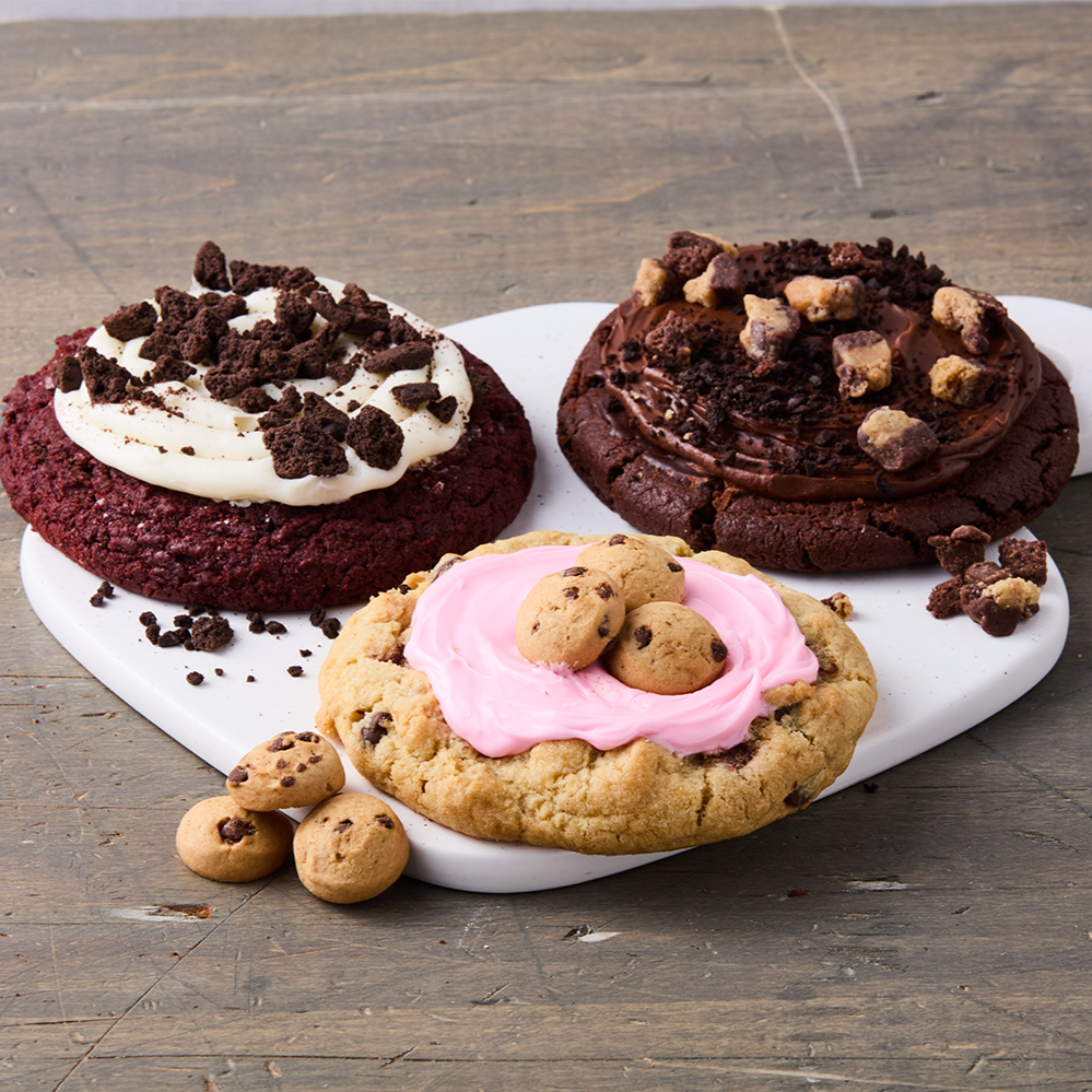 Three decorated cookies on a white platter placed on a wooden table.