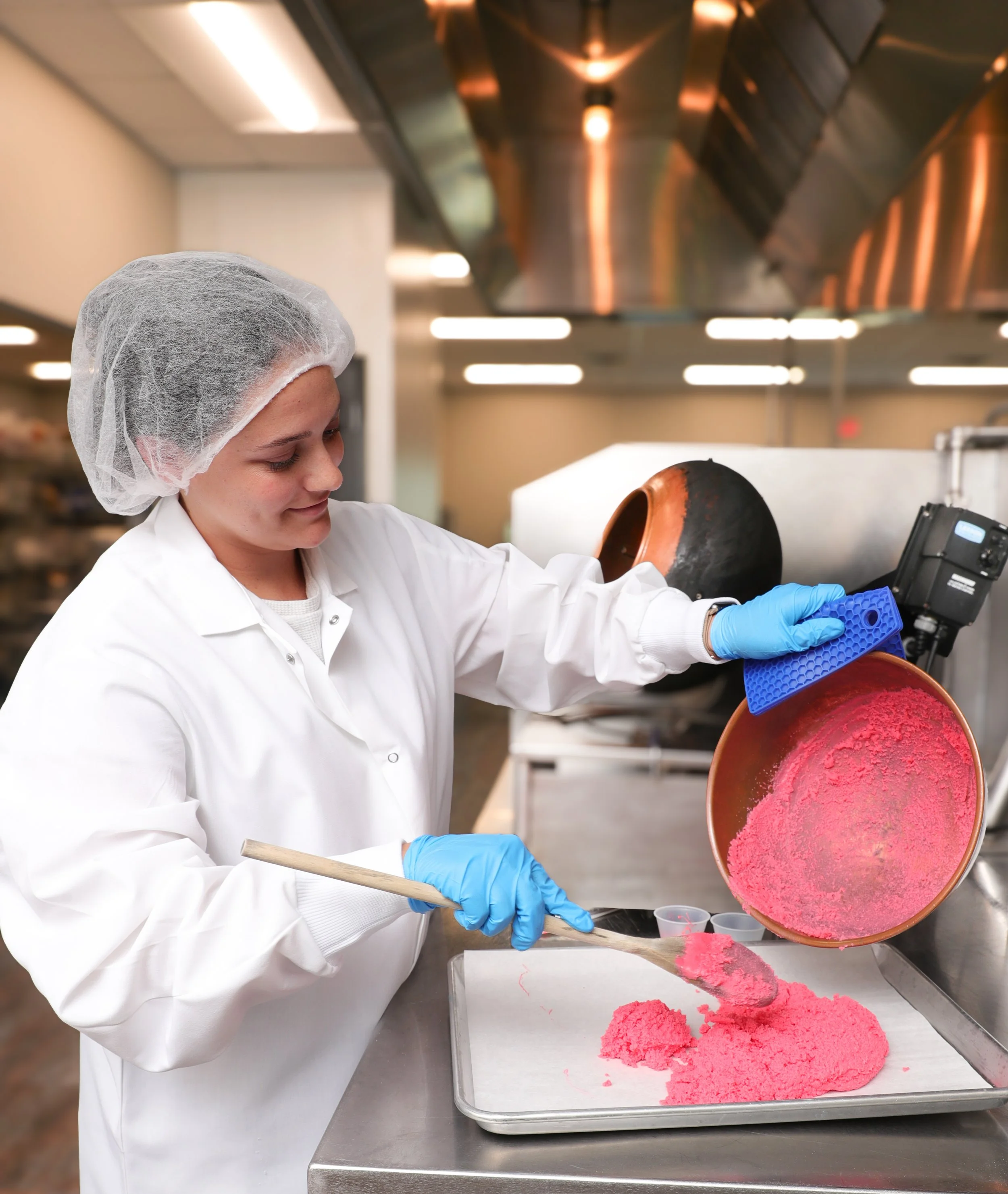 Food technologist preparing bright pink confectionary inclusions in a commercial kitchen, showcasing innovative toppings and mix-ins for desserts.