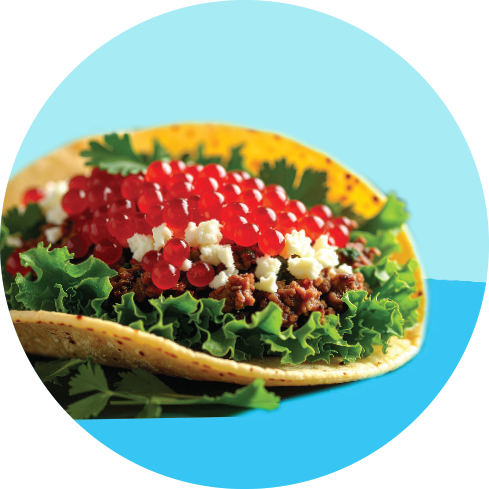Taco filled with ground beef, lettuce, cheese, red caviar, and garnished with green herbs.