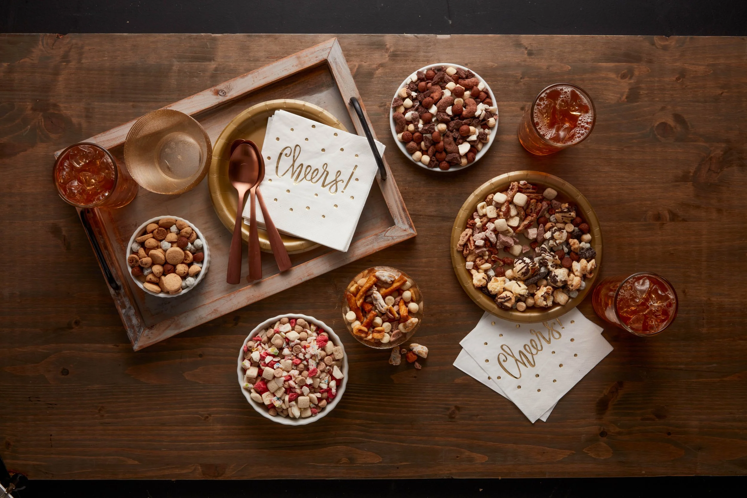 Tablespread with bowls of cookies, candies, and three drinks, along with a tray holding napkins and utensils.