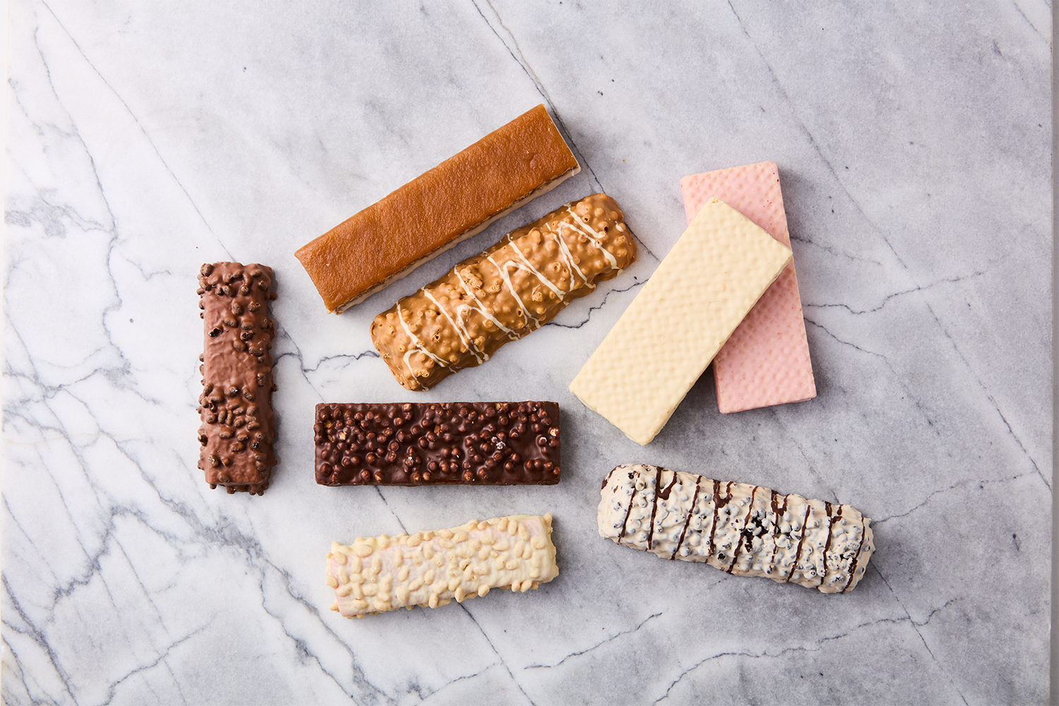 Assorted cereal bars with different flavors and toppings arranged on a gray marble surface.