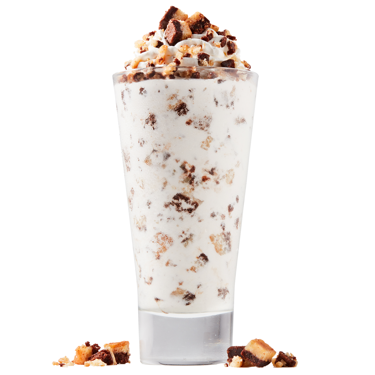A tall glass filled with cookies and cream milkshake topped with whipped cream and cookie crumbles, with some cookie pieces scattered at the base.