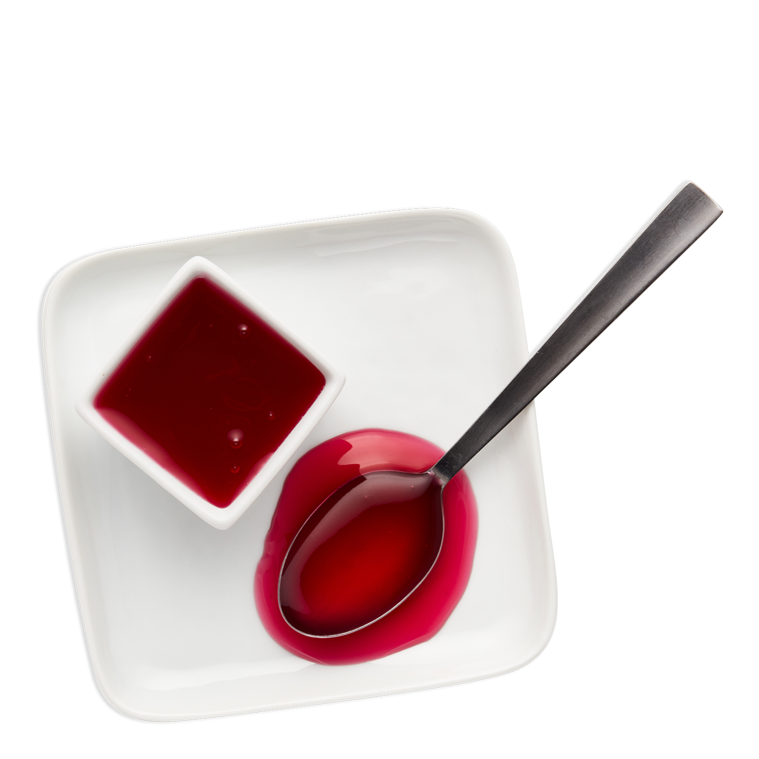 A white square plate with a small square dish and a spoon filled with red liquid, set against a black background.
