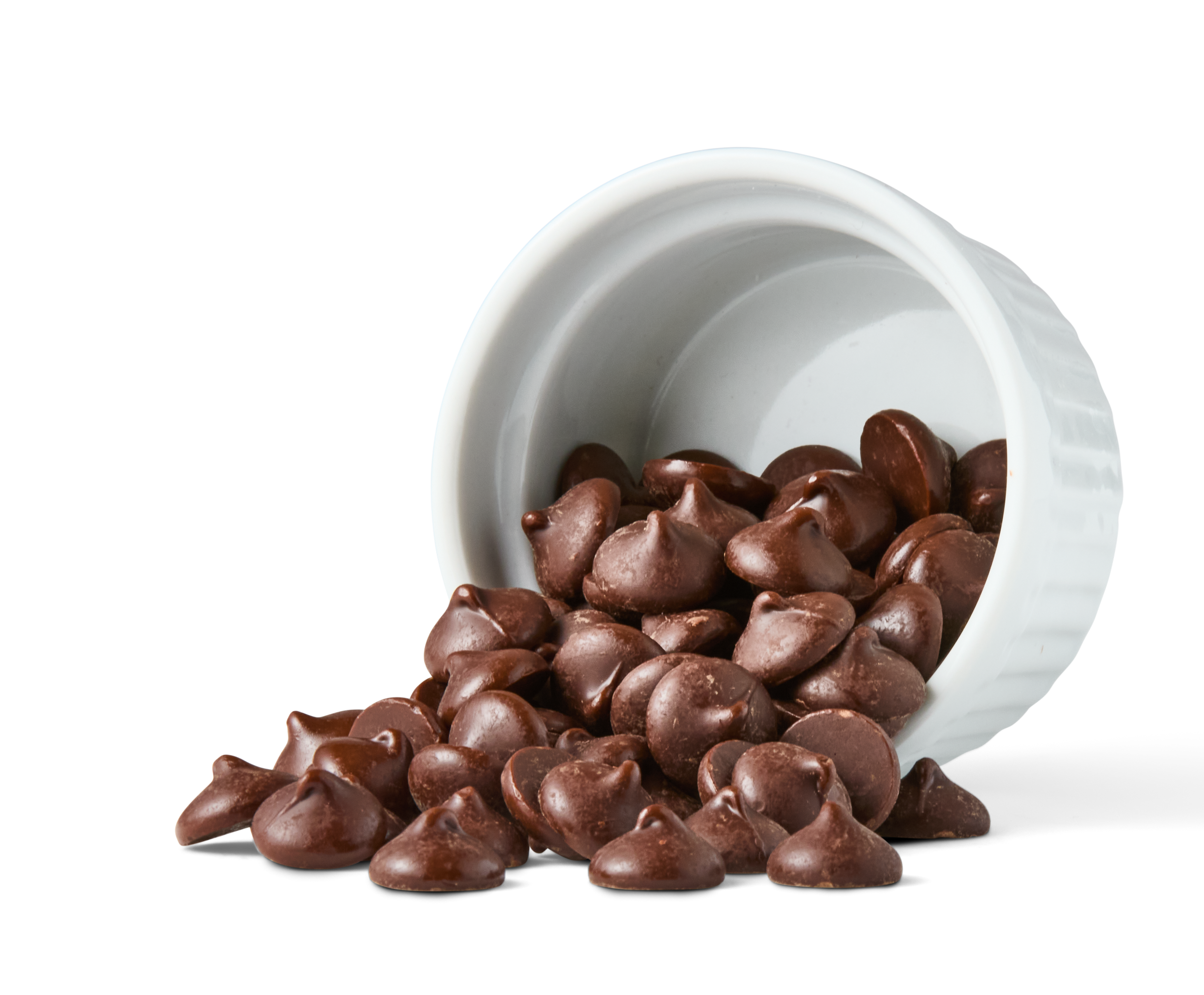 A white ceramic container tipped over spilling chocolate chips onto a surface.
