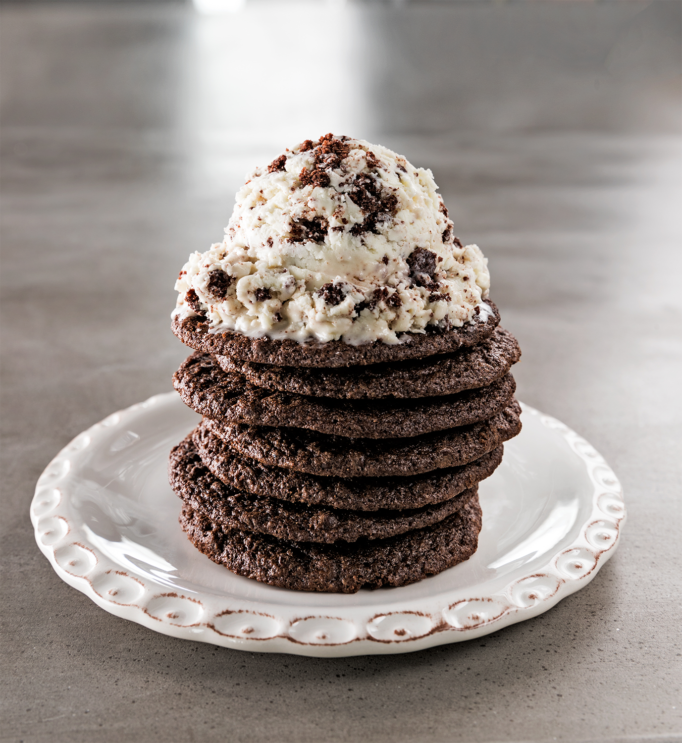 Stack of chocolate cookies topped with a scoop of cookies and cream ice cream with chocolate chunks