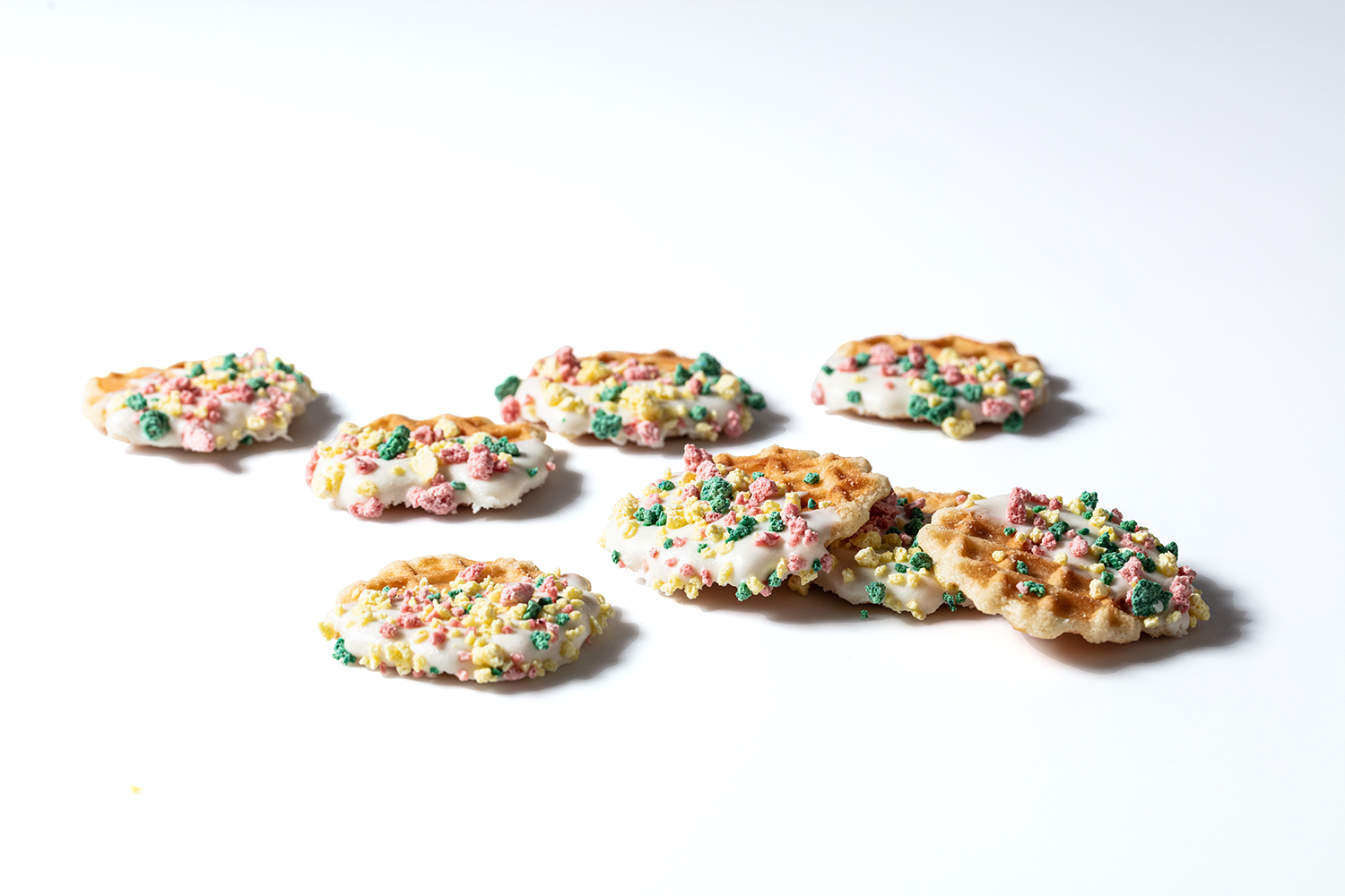 Several sprinkled cookies with white icing on a white background.