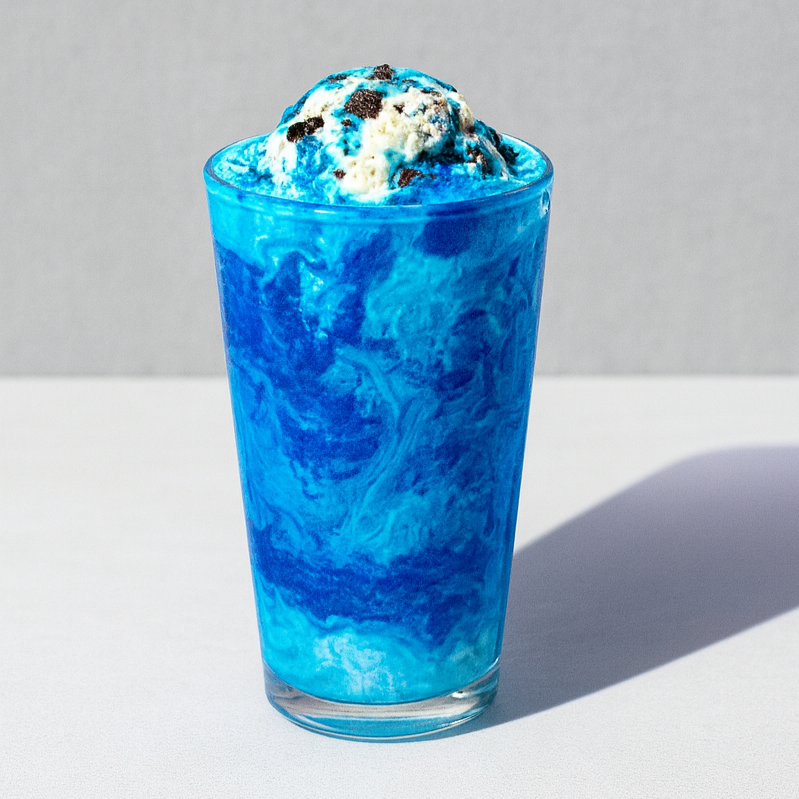 Blue marble-patterned glass filled with cookies and cream ice cream topped with chocolate cookie crumbs, on a white surface with a gray background.