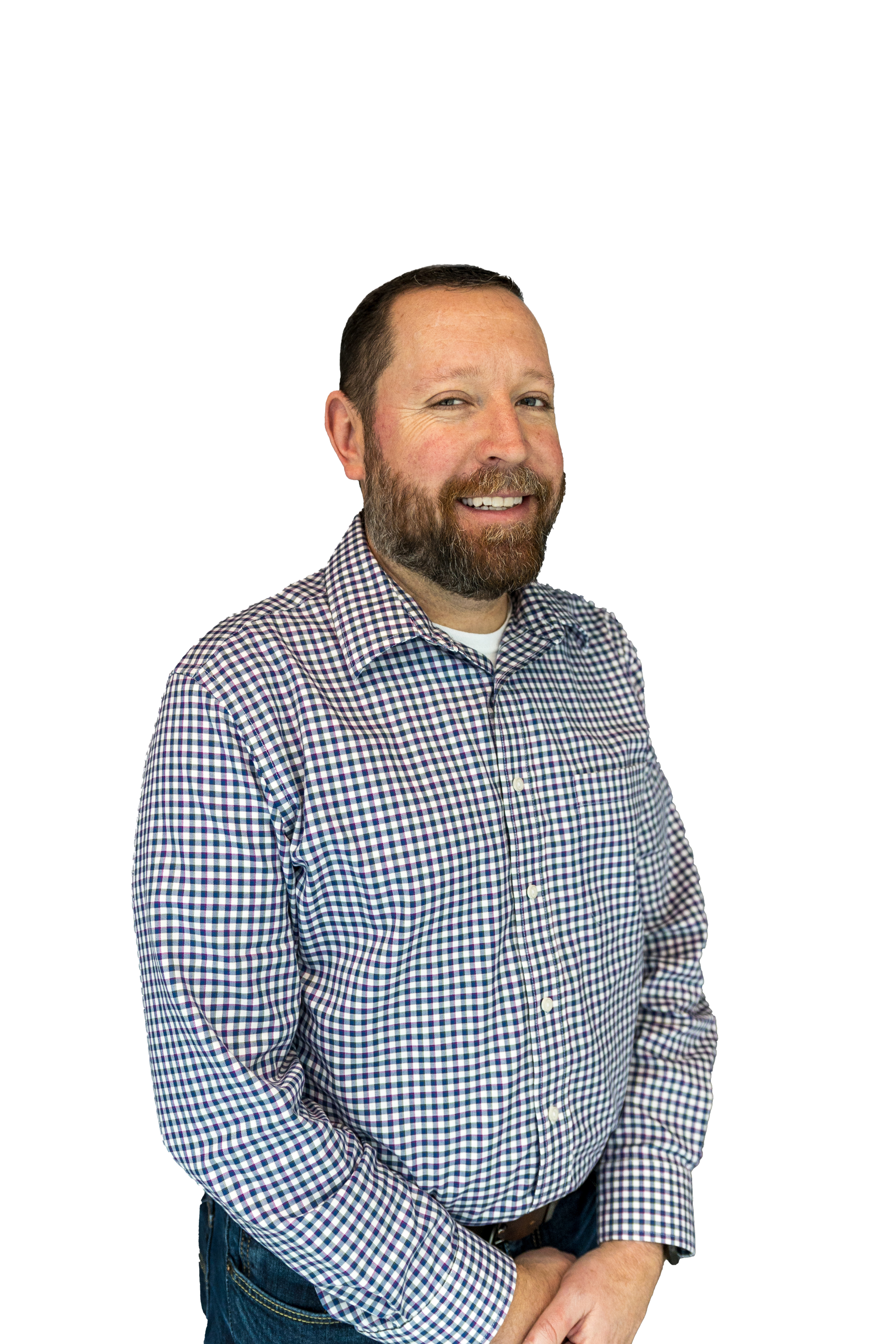 A middle-aged man with short dark hair and a beard, smiling and crossing his arms, wearing a checkered shirt and jeans.