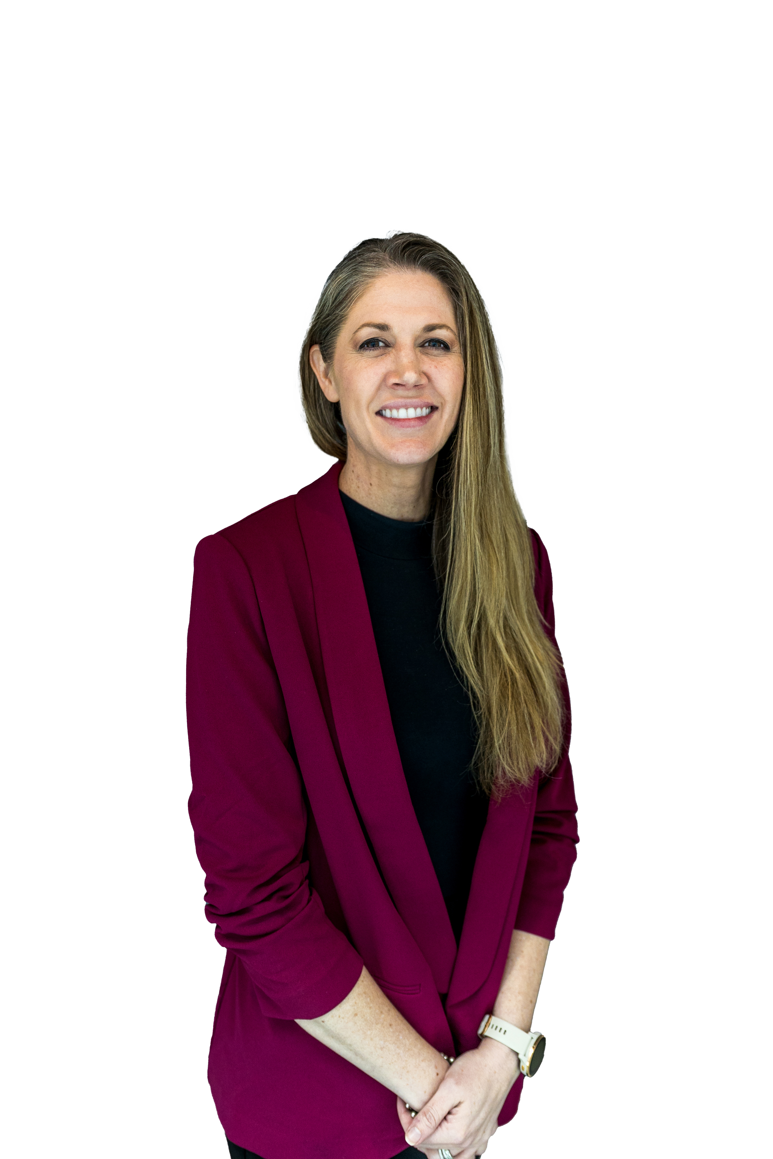 A woman with long, light brown hair, wearing a burgundy blazer over a black top, standing with her hands clasped in front of her, smiling, against a colorful geometric background.