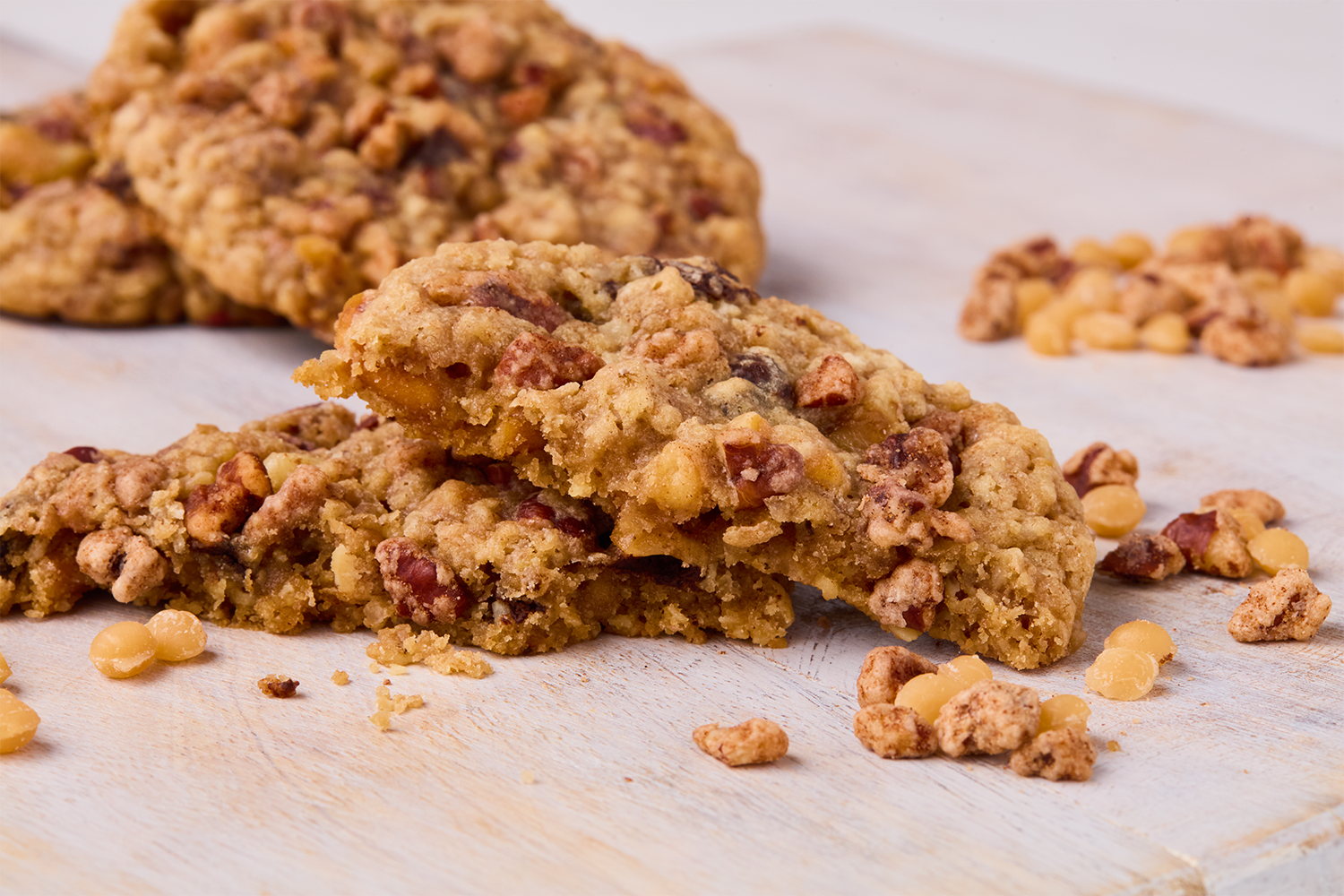Close-up of homemade peanut butter chocolate chip cookies on a wooden surface, with some scattered nuts.