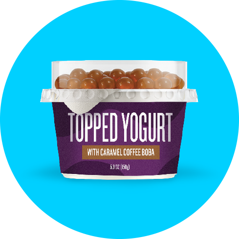 Container of topped yogurt with caramel coffee boba against a blue background.