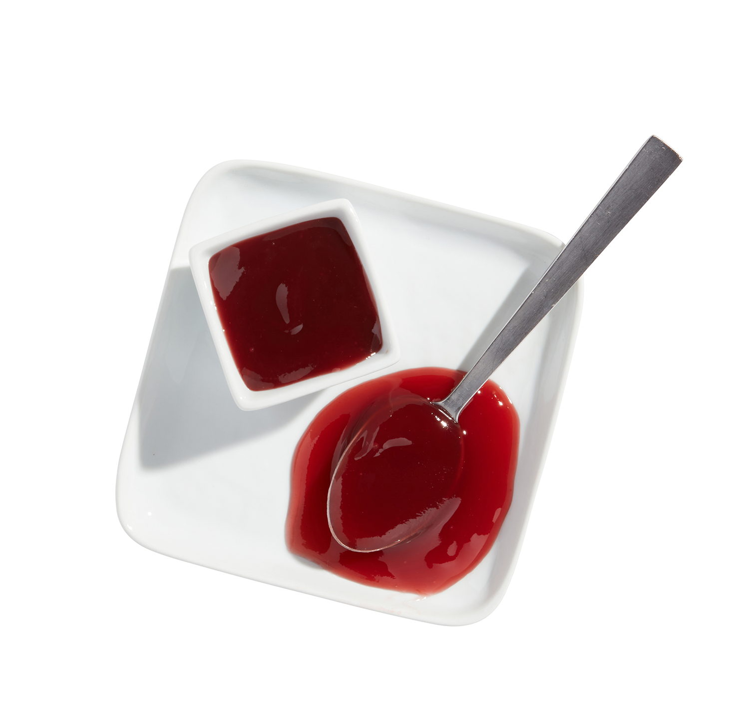Spoon with strawberry jam on white square dish, additional dish of strawberry jam beside it, on white background