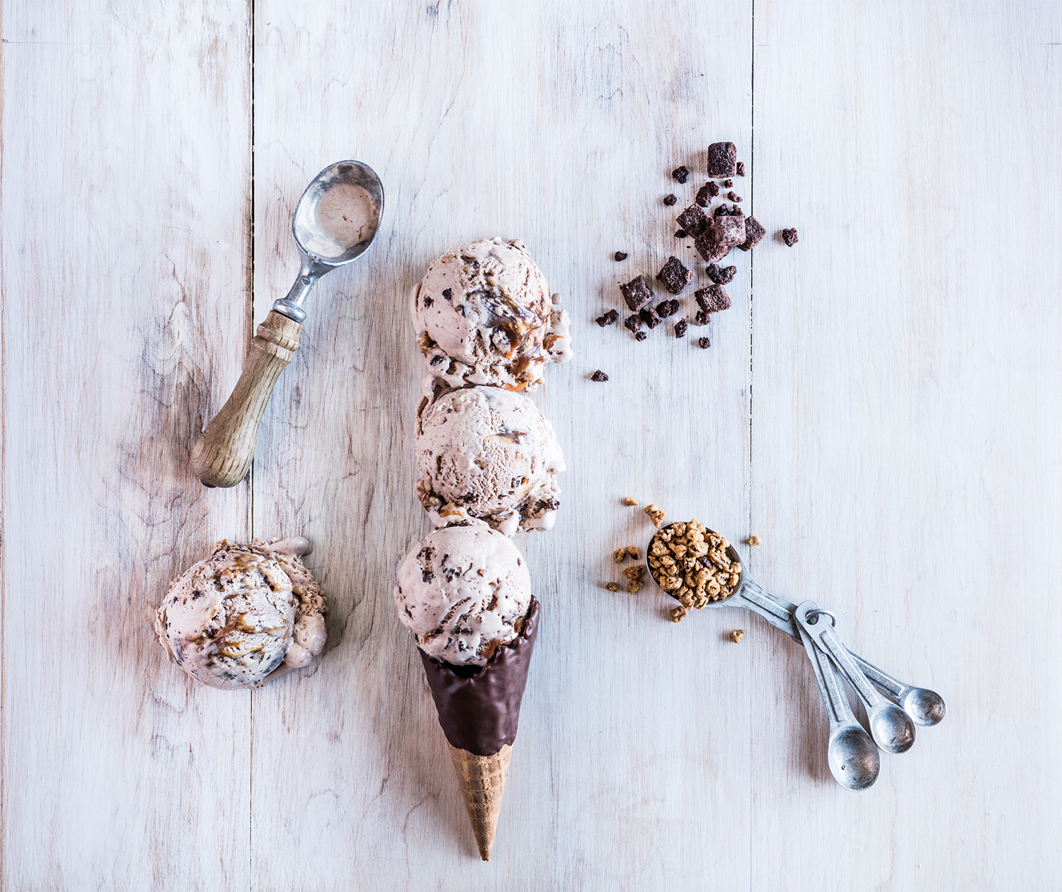 Whisky River Ice cream cone with chocolate coating, three scoops of ice cream topped with chocolate and caramel, scattered chocolate and caramel chunks.