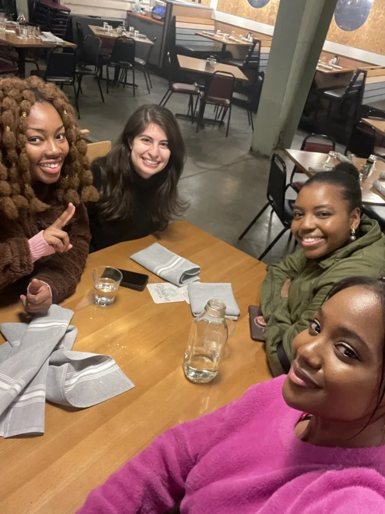 Four women sitting at a restaurant table, smiling and posing for a photo.