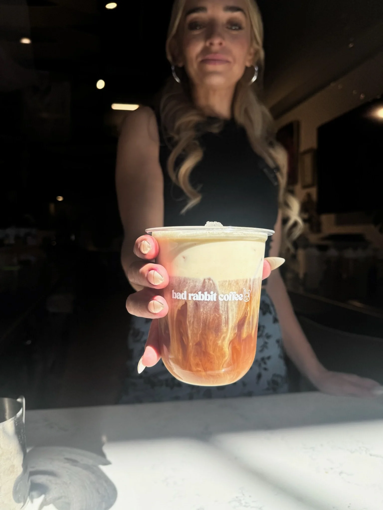 Person holding a cup of coffee in a coffee shop
