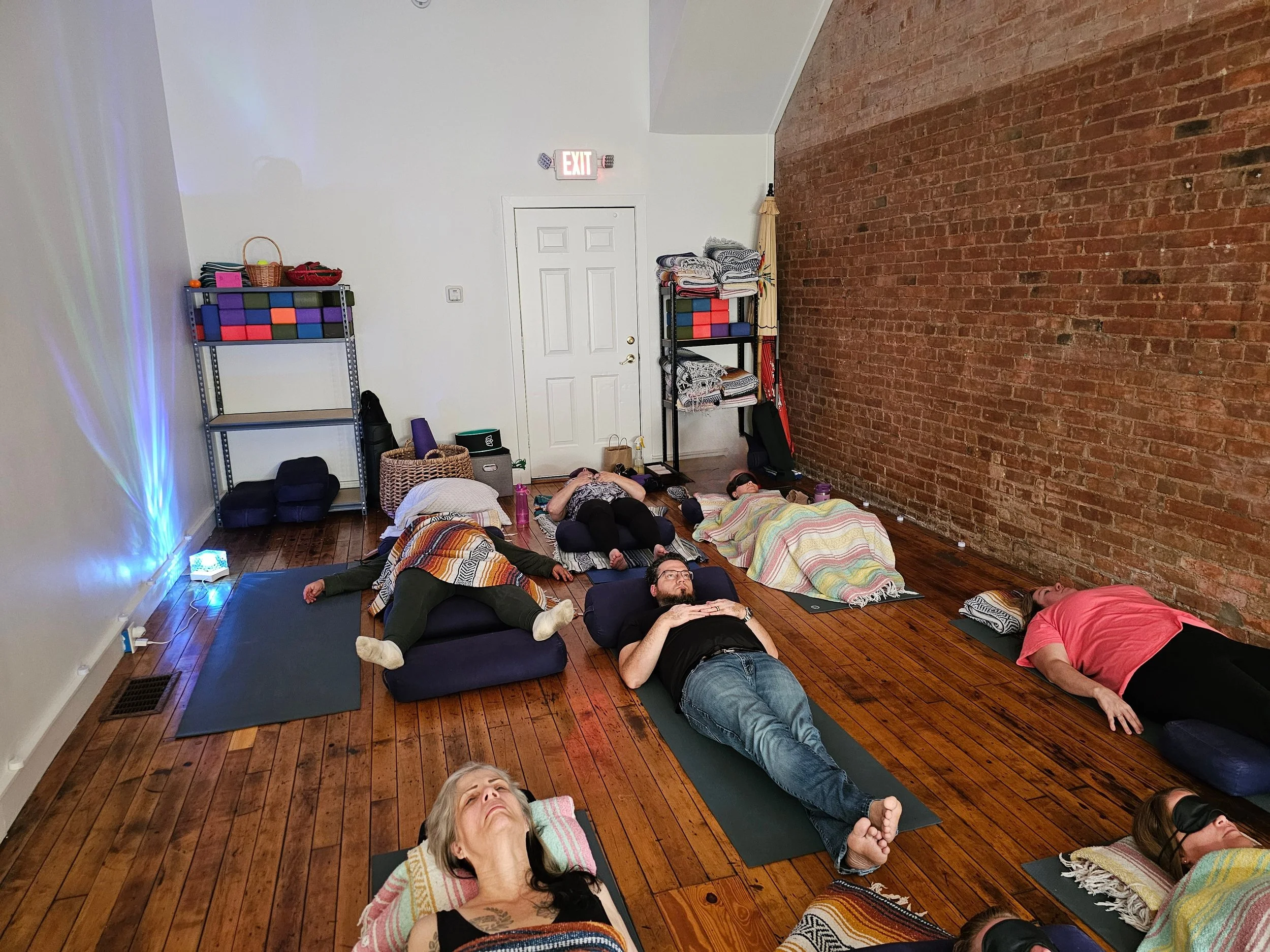 people laying on yoga mats receiving acupuncture in a community setting