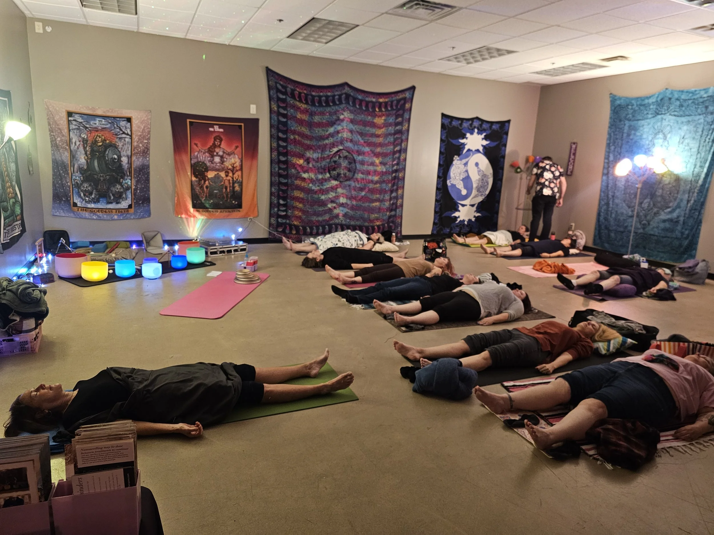 People laying on yoga mats in rows during a sound bath with acupuncture