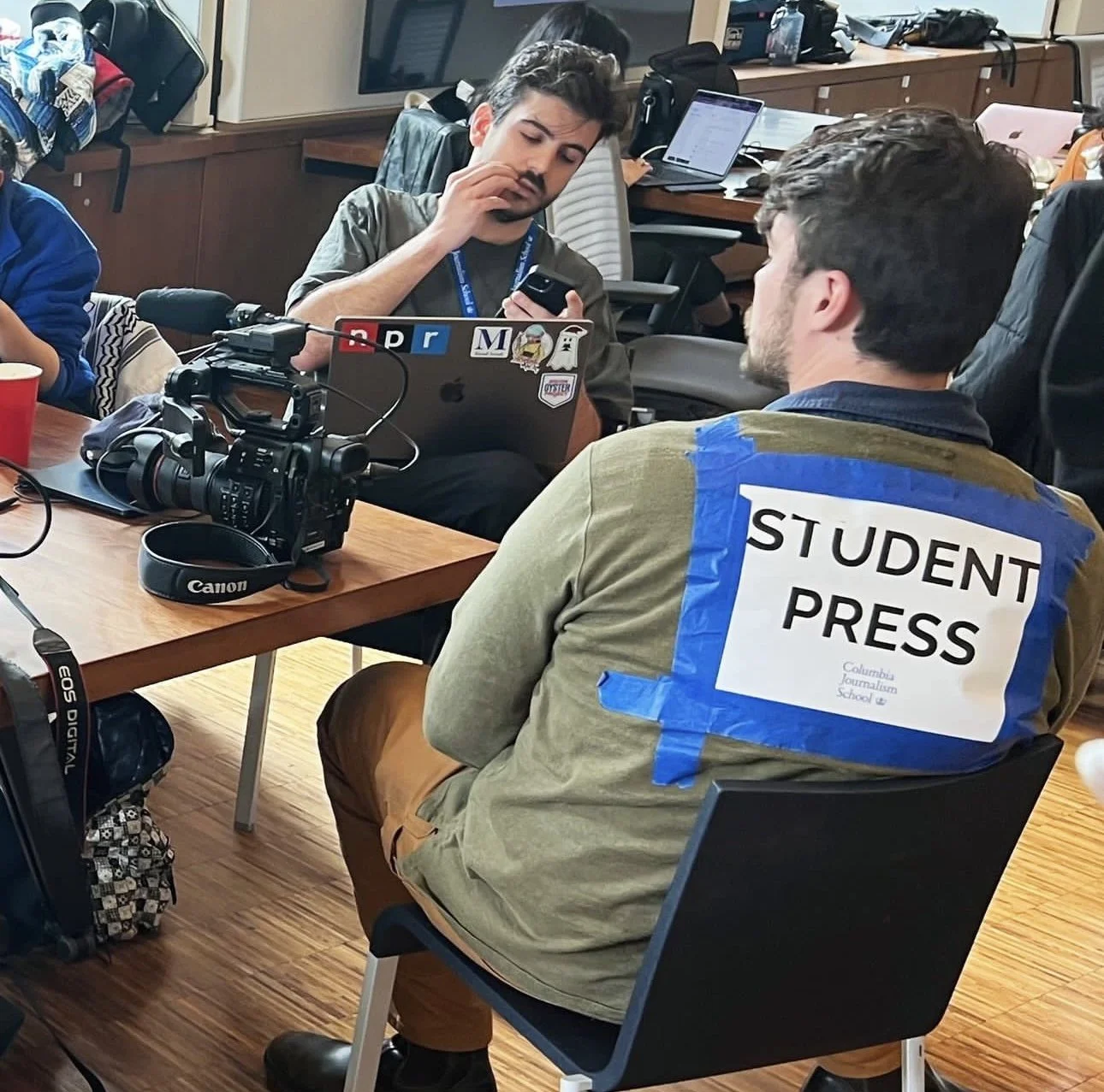 Brendan wearing a "Student Press" sign so that he is clearly visible to the police as a reporter while covering the encampment. 